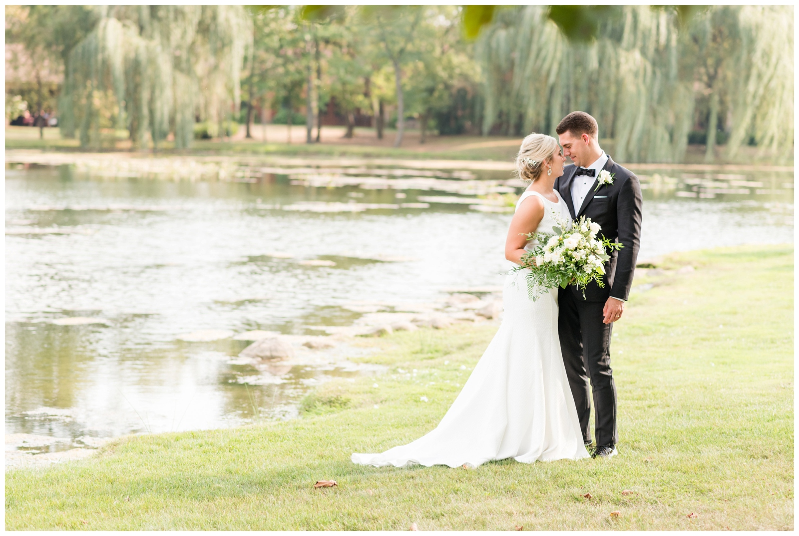 bride and groom touch noses by pond at Gervasi Vineyard in Canton OH