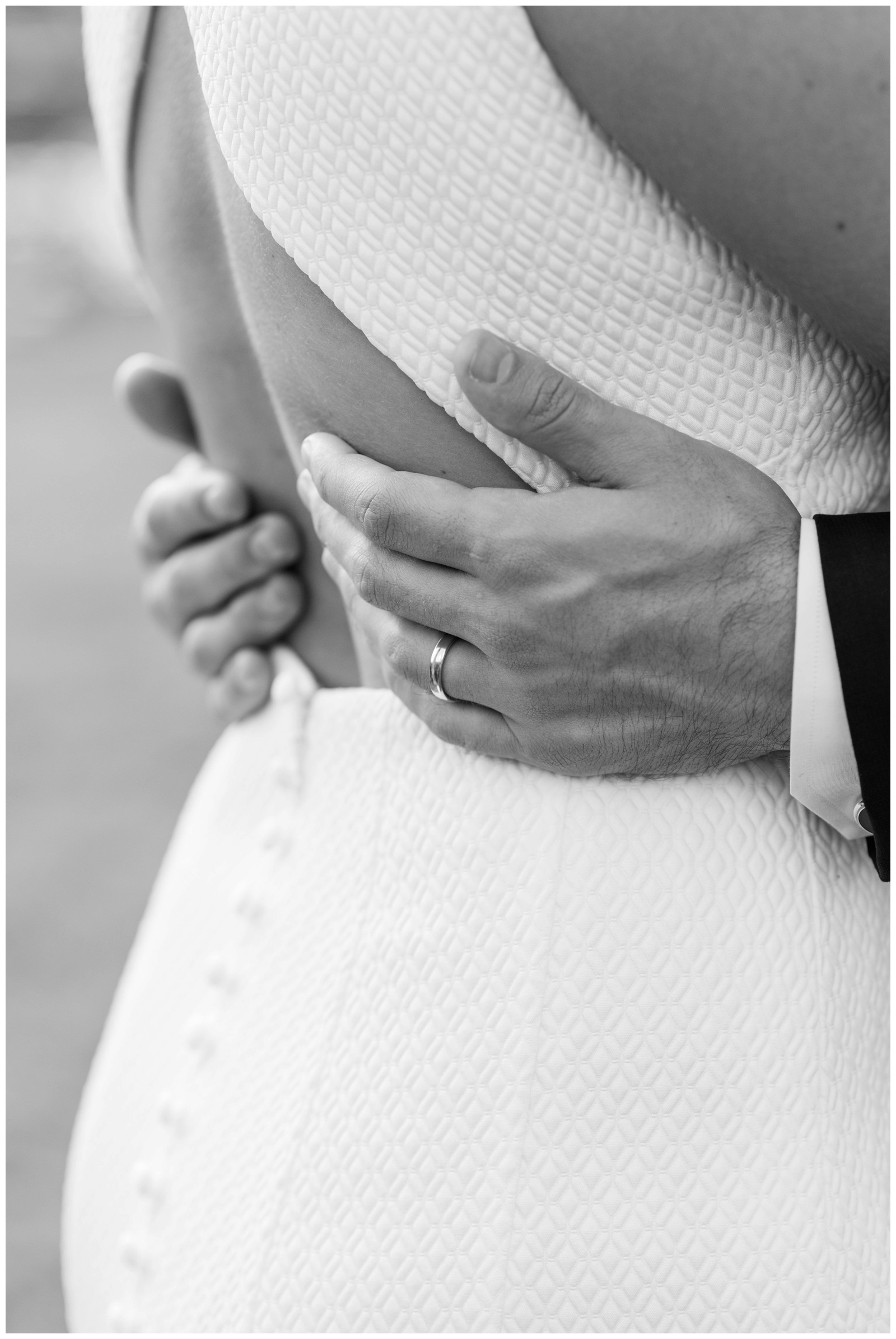 close up portrait of groom's ring while he holds bride's back