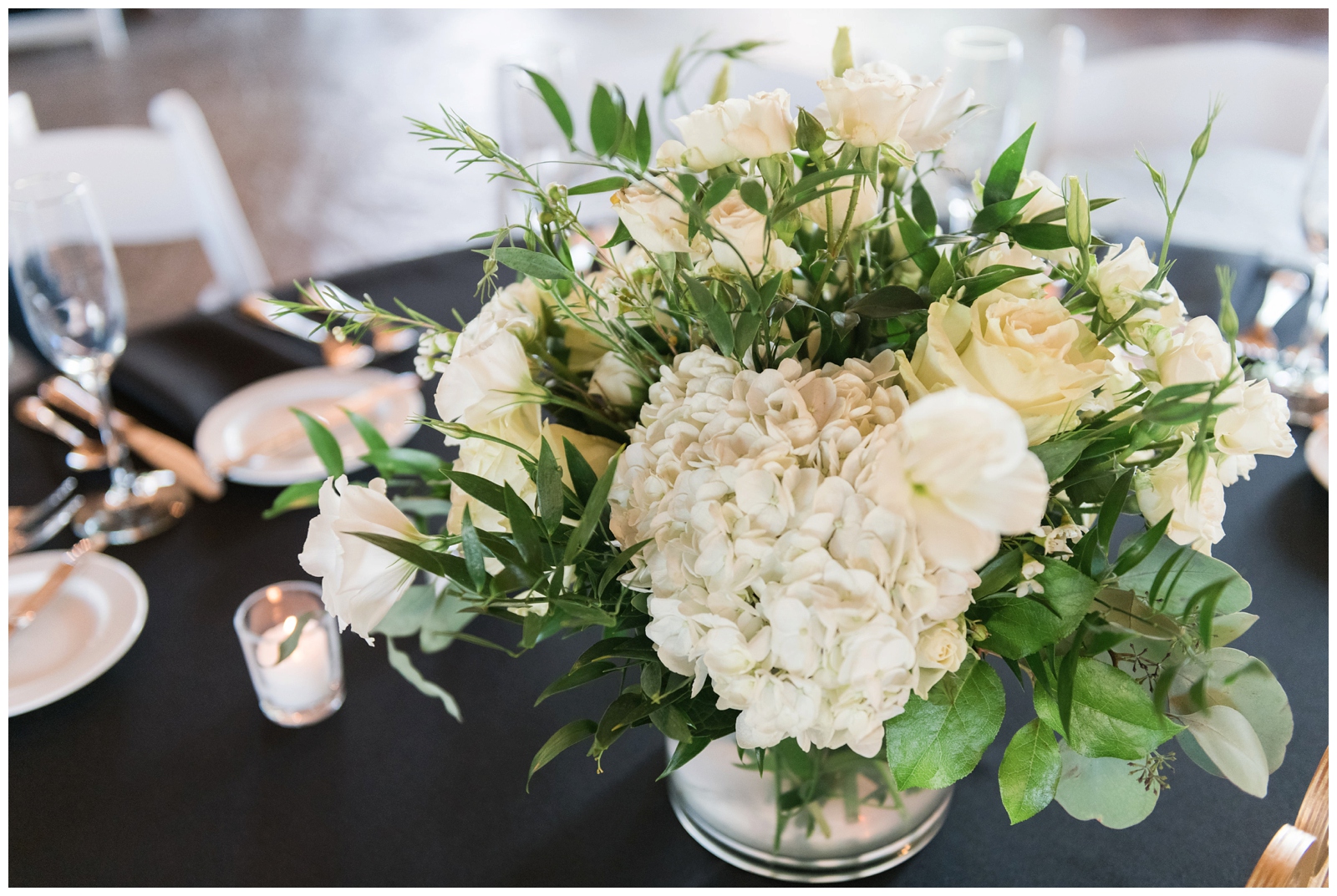 all-white floral centerpieces on black tablecloth at Gervasi Vineyard
