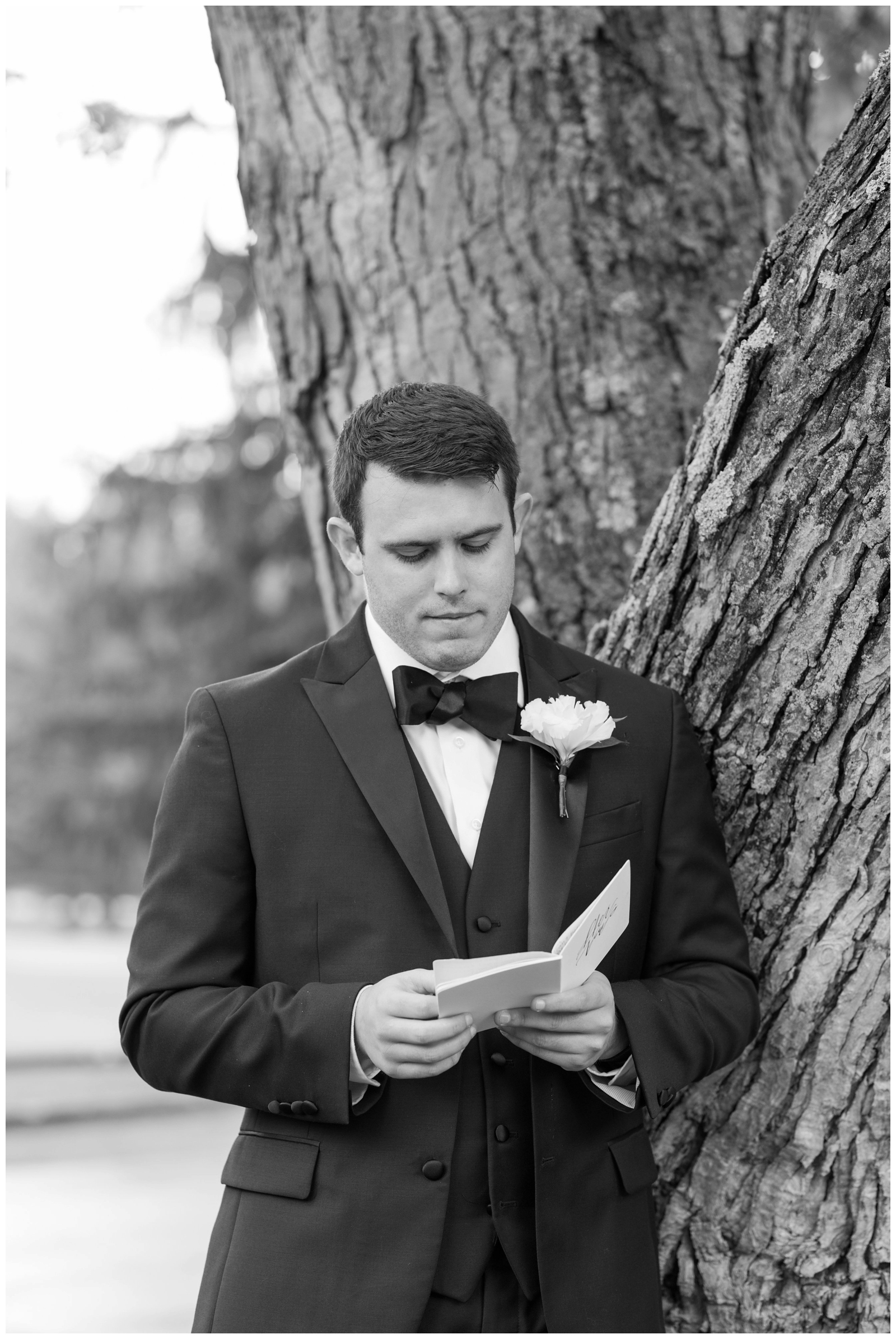 groom reads bride's vows in her booklet outside by a tree in Ohio