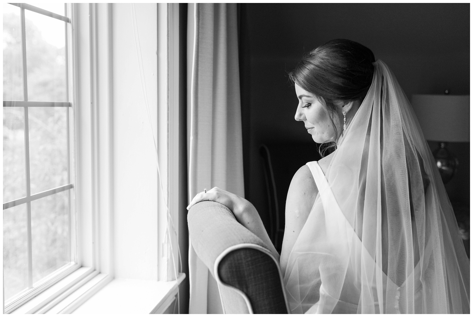 bride looks out window at Brookside Golf and Country Club for bridal portrait with her veil