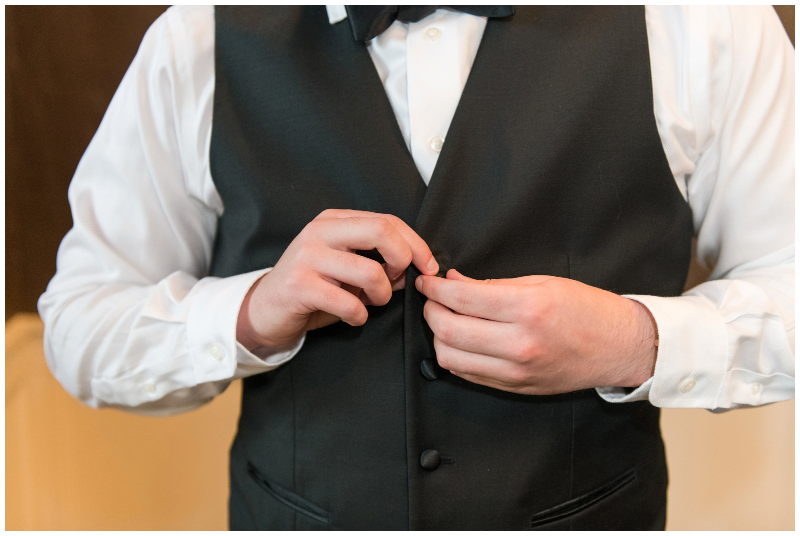 groom adjusts buttons on tux vets before Columbus OH wedding day