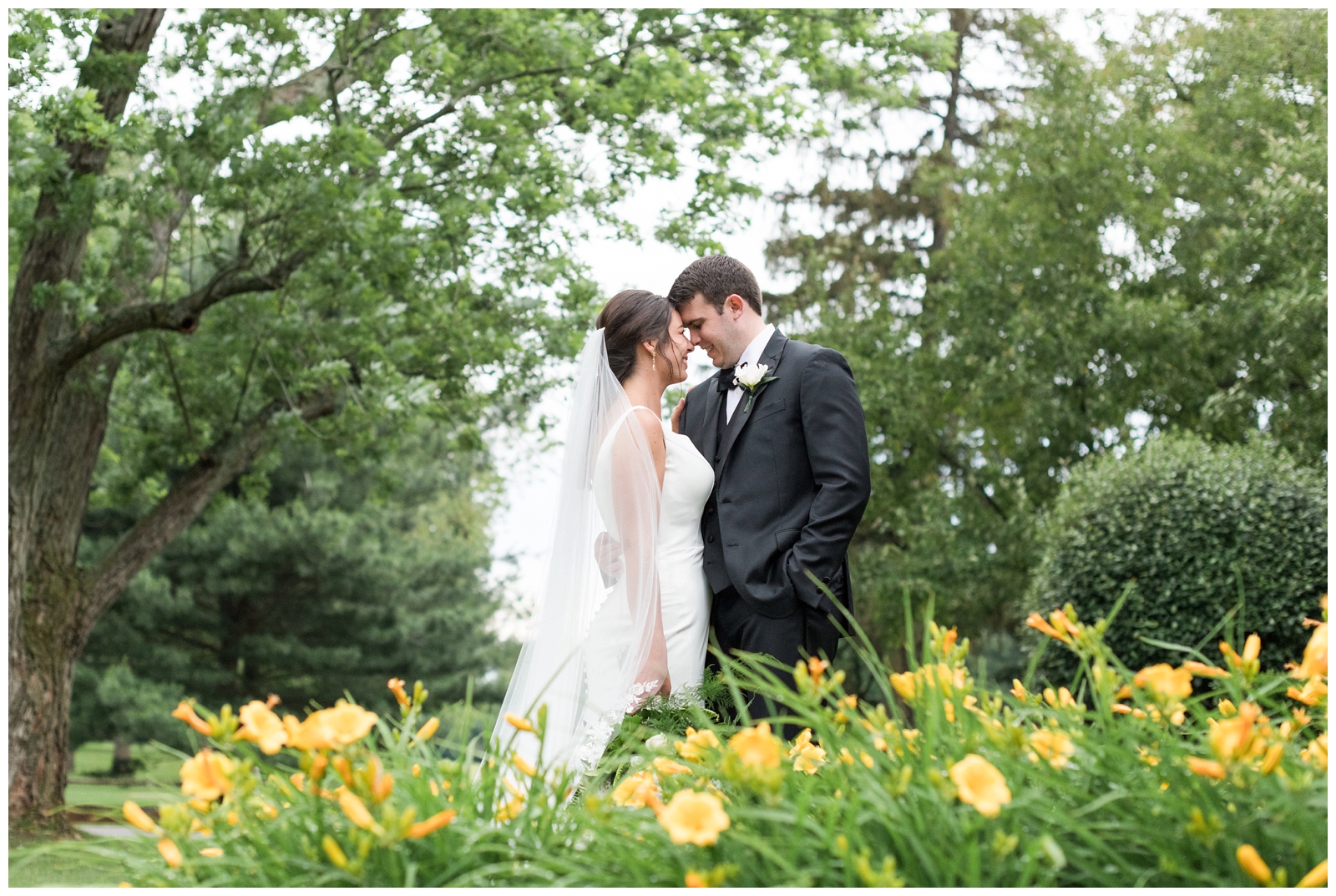 groom holds bride close during Ohio wedding portraits among yellow flowers at Brookside Golf and Country Club 