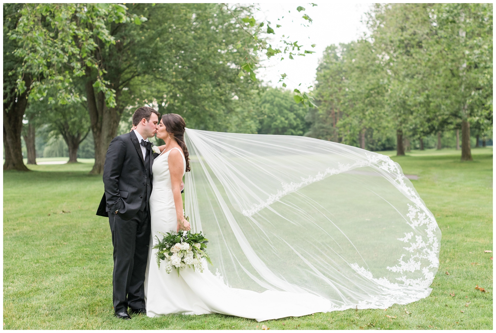 bride and groom kiss while bride's veil blows in the wind at Brookside Golf and Country Club 