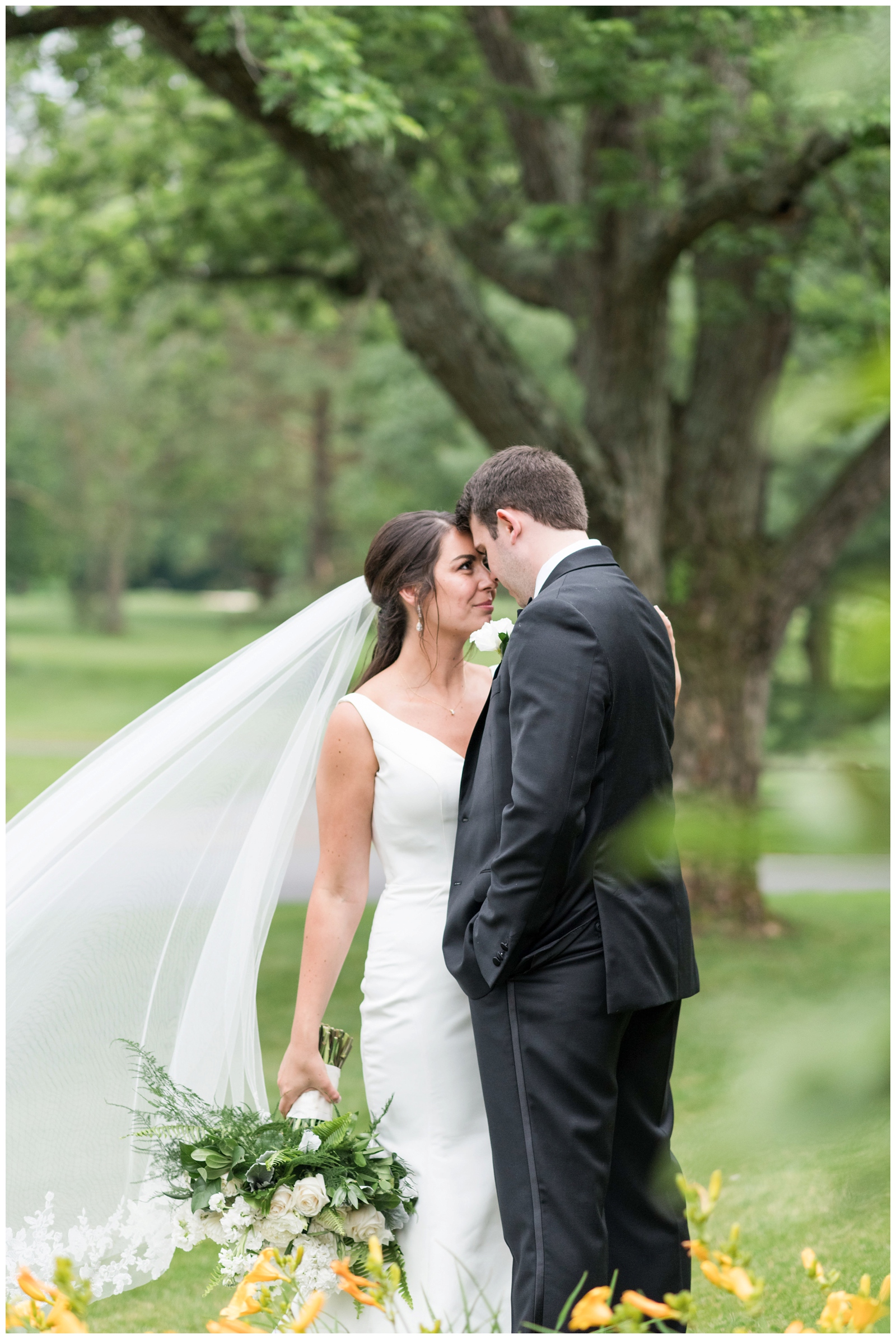 bride and groom nuzzle noses in garden of yellow flowers at Brookside Golf and Country Club 