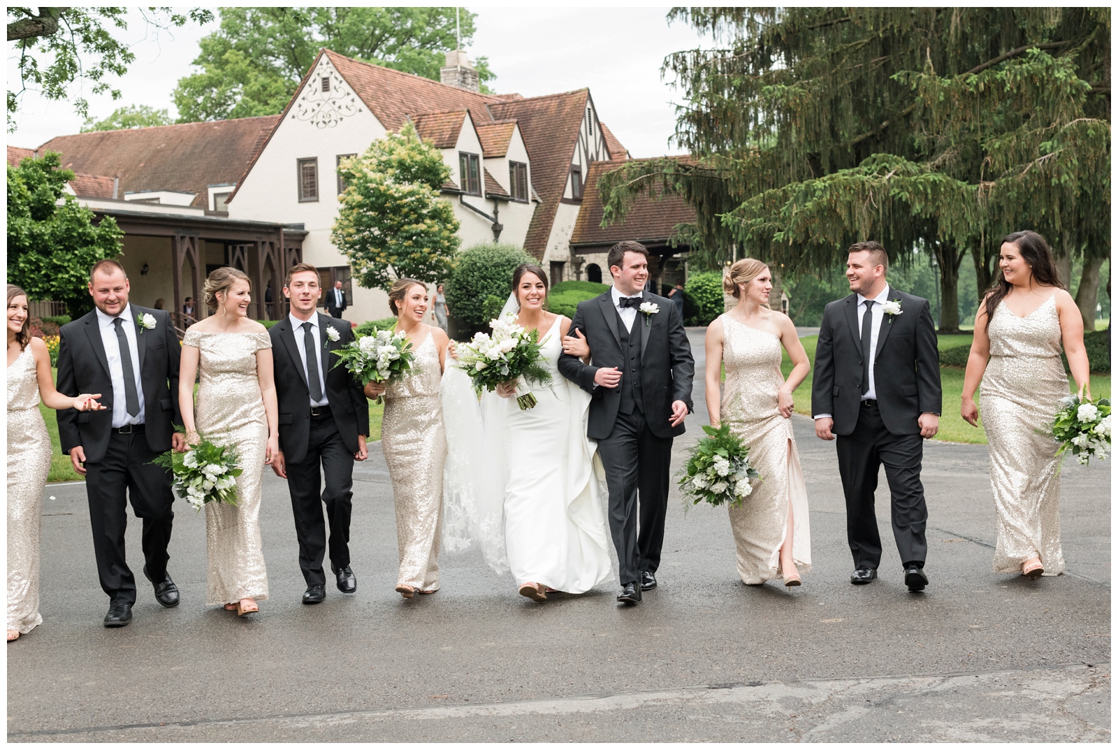 bridal party walks in gold gowns during wedding portraits at Brookside Golf and Country Club 
