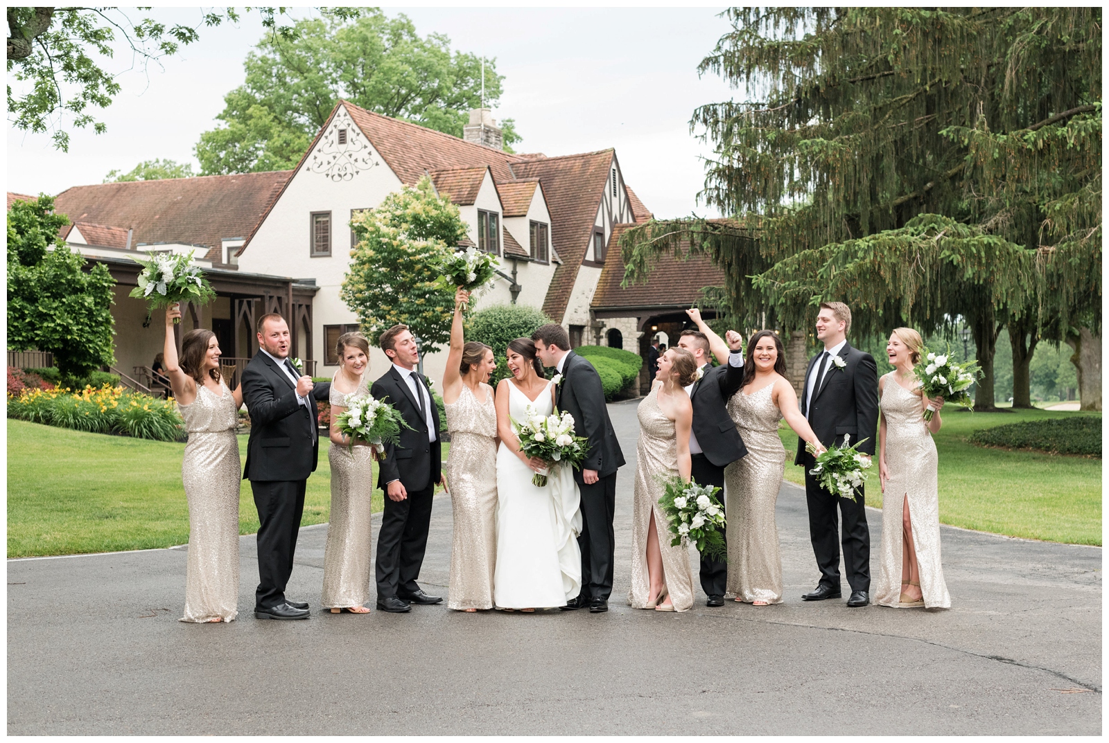 bridesmaids hold bouquets in the air during bridal party portraits out front at Brookside Golf and Country Club 