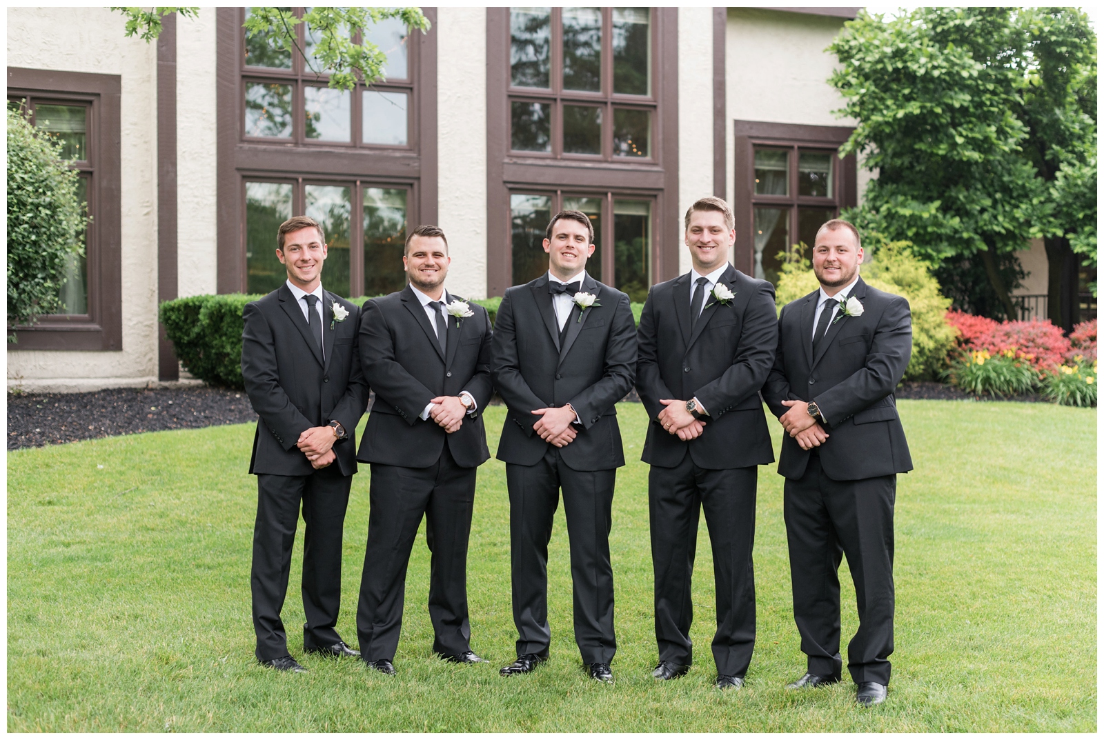 groom and four groomsmen pose outside Brookside Golf and Country Club with hands crossed over each other