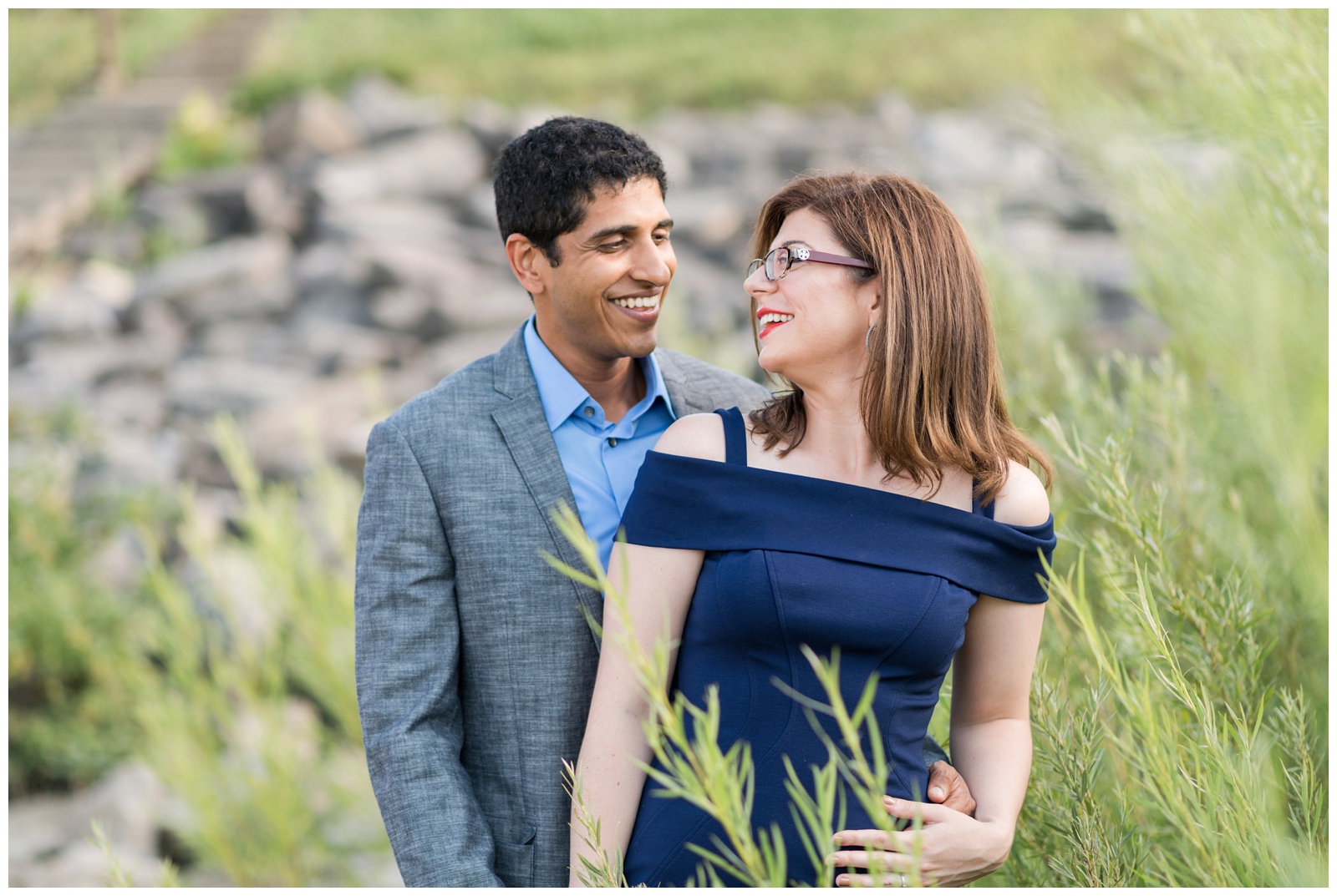 soon-to-be married couple look at each other smiling in field during Hoover Reservoir engagement portraits by Pipers Photography