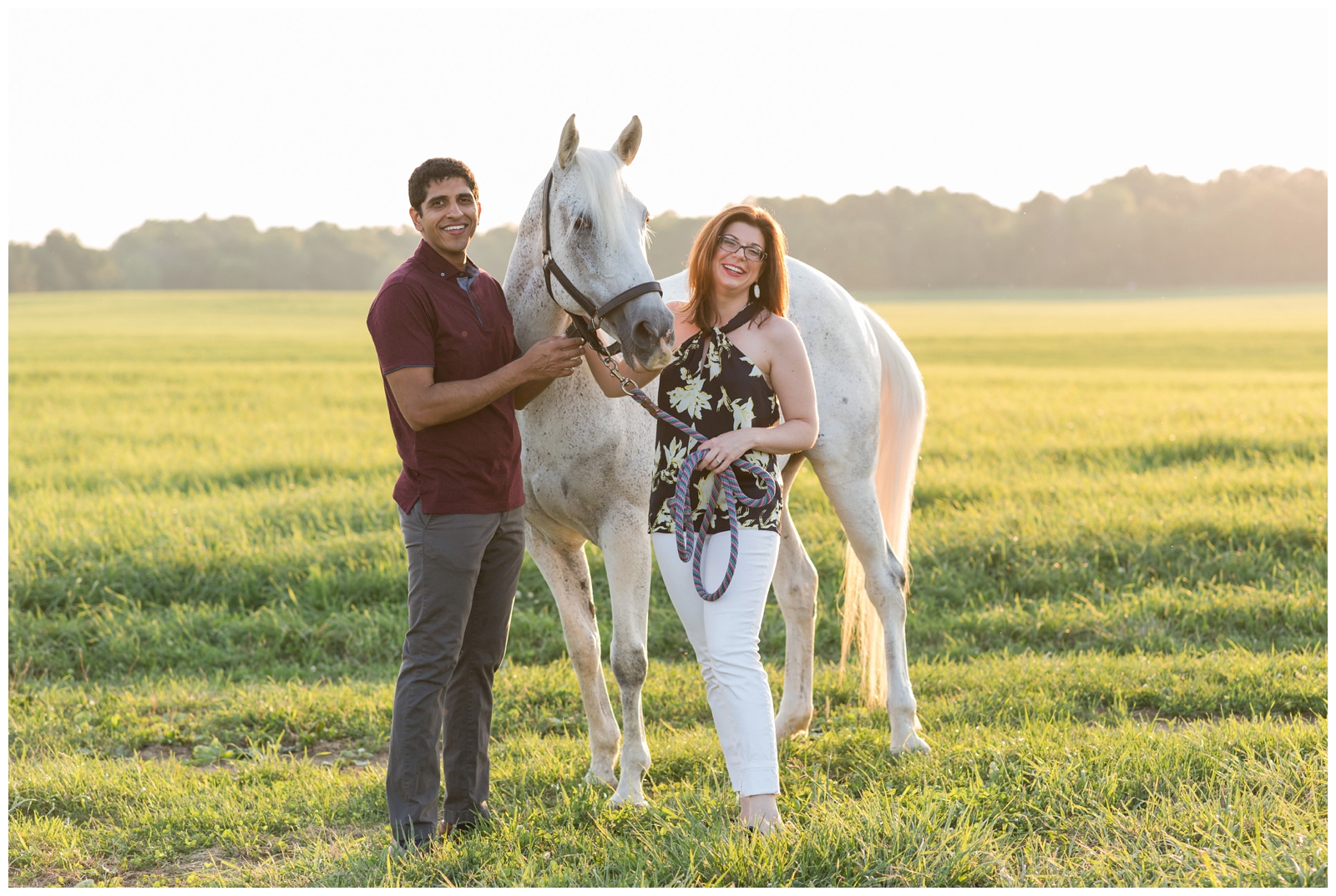 groom in red shirt and bride in floral top pose with white horse in Ohio field during engagement portraits