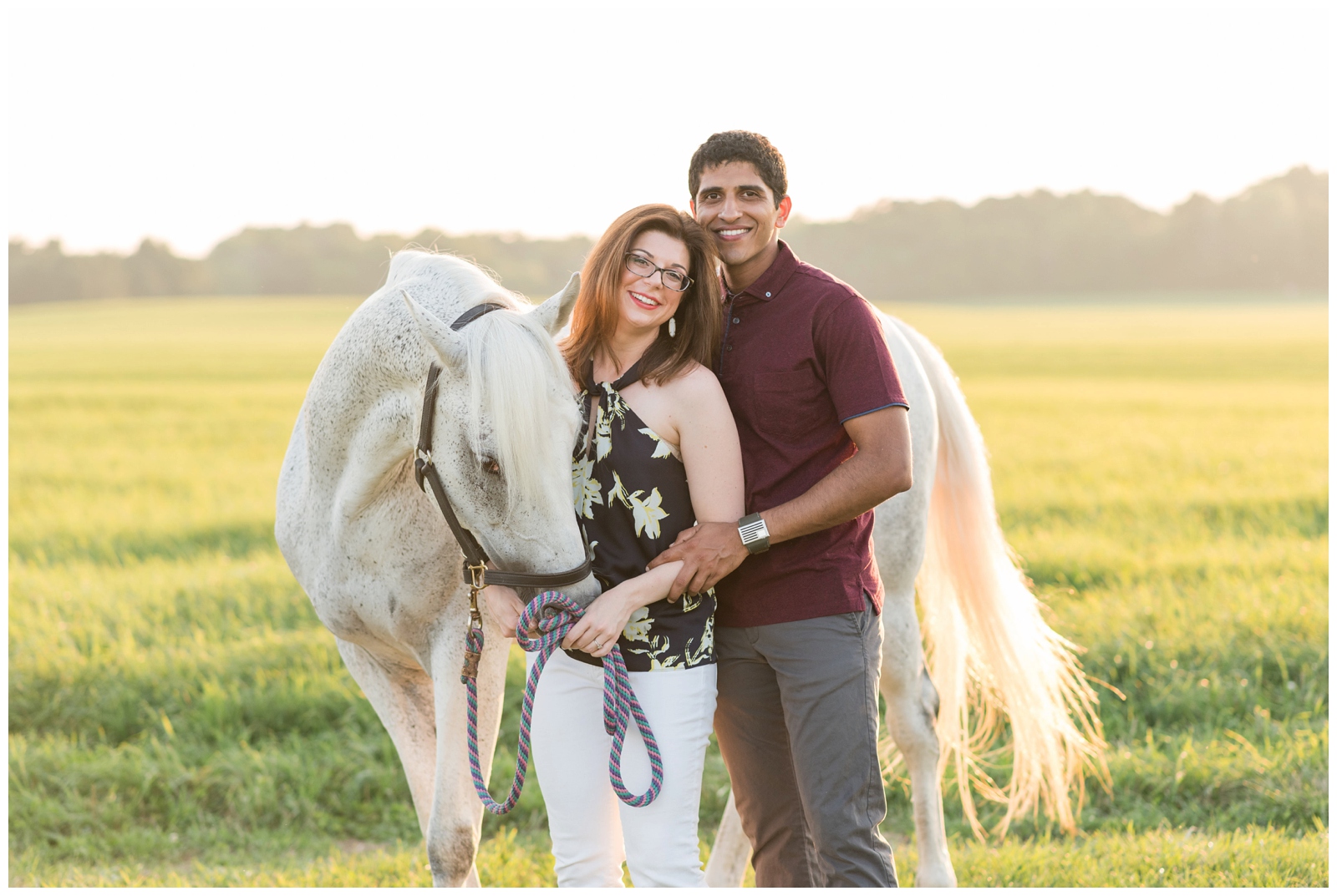 bride holds white horse's reins during engagement portraits in field