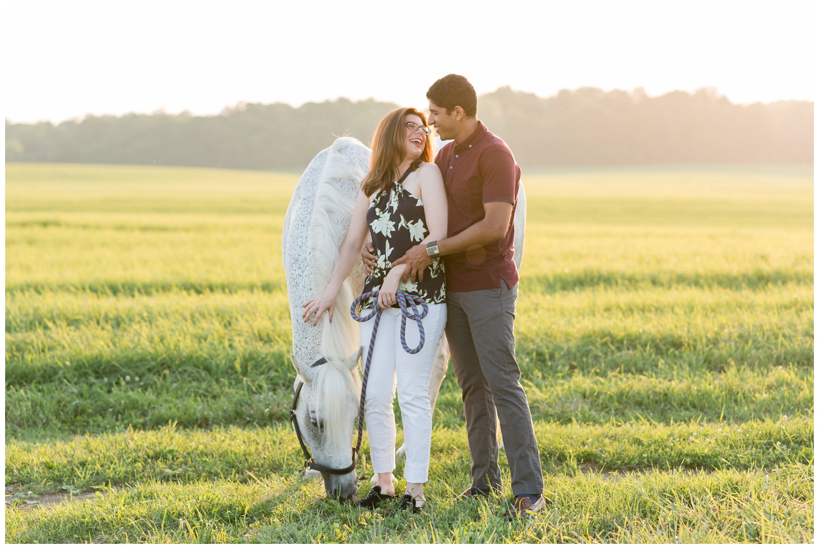 bride pets white horse in field with groom in red polo photographed by Pipers Photography