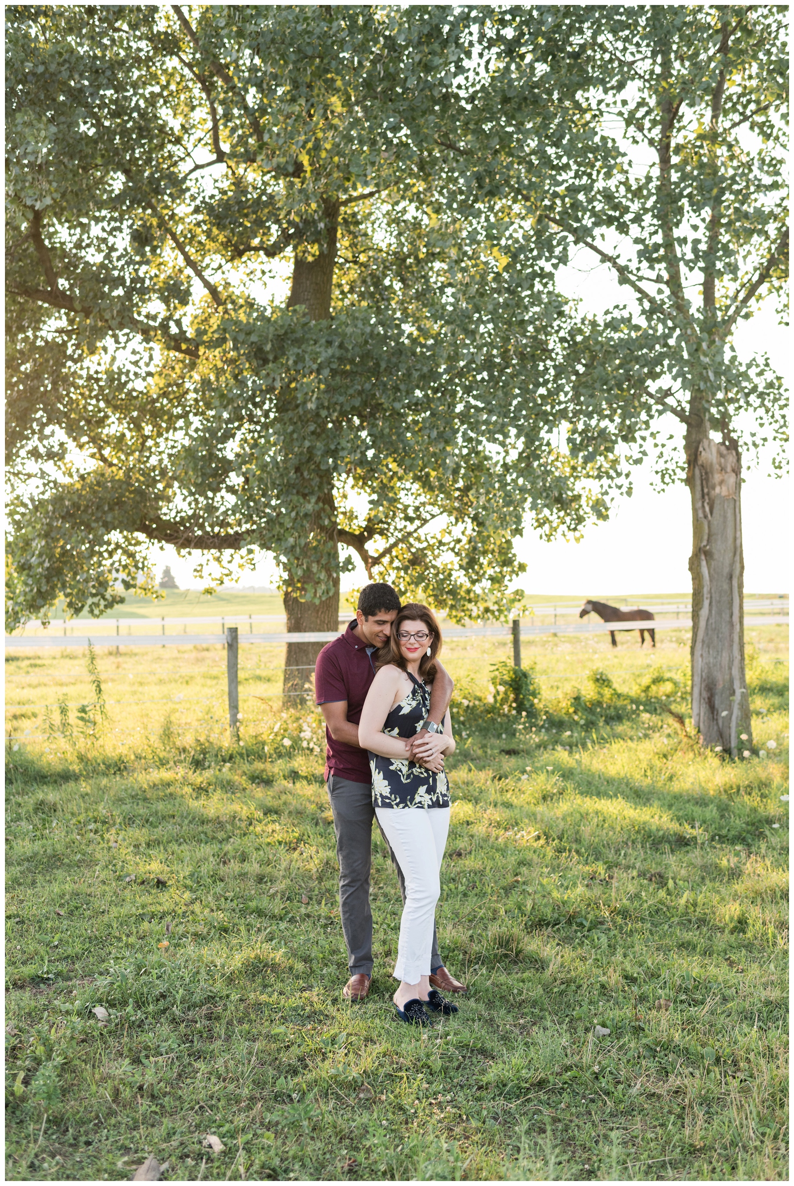 bride and groom embrace during engagement session on edge of horse pasture by Pipers Photography