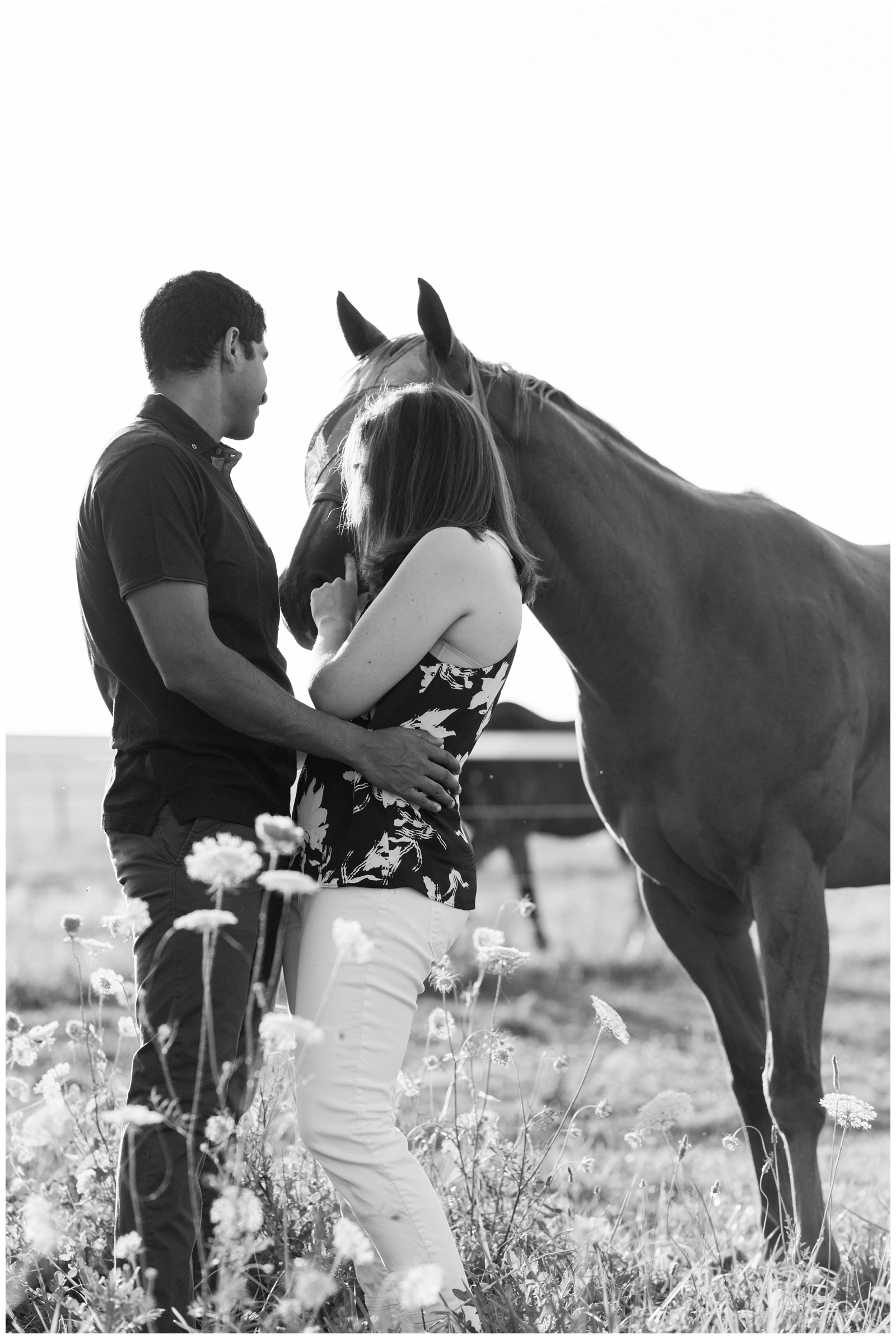 black and white portrait of bride and groom during engagement session while horse interrupts