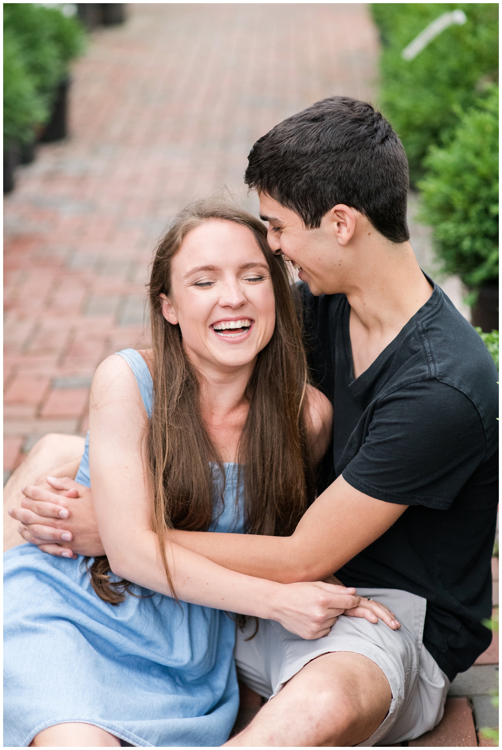 young engaged couple laughs while sitting on brick walkway during New Albany Ohio engagement session