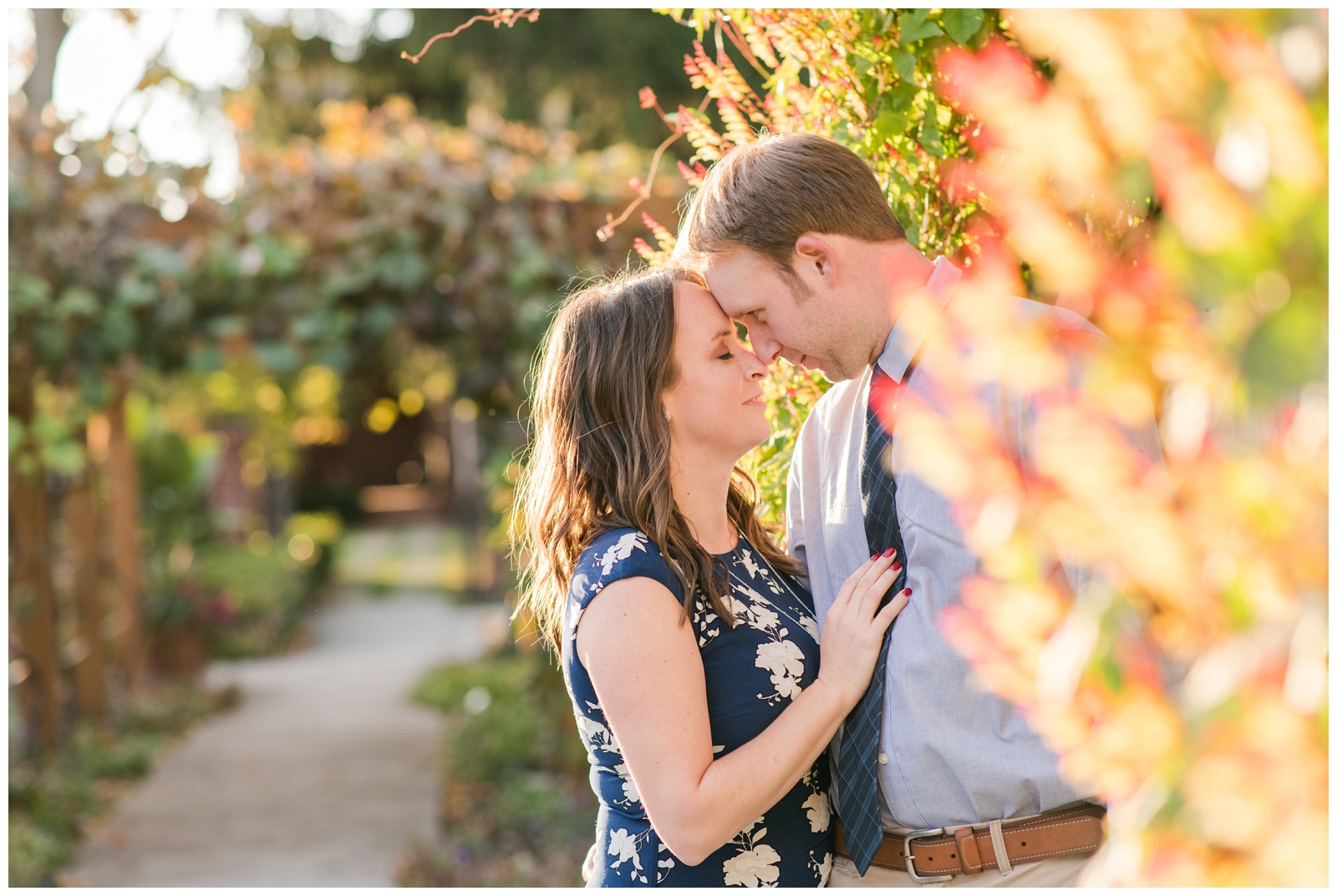 engaged couple touches noses between orange and yellow trees at Franklin Park Conservatory