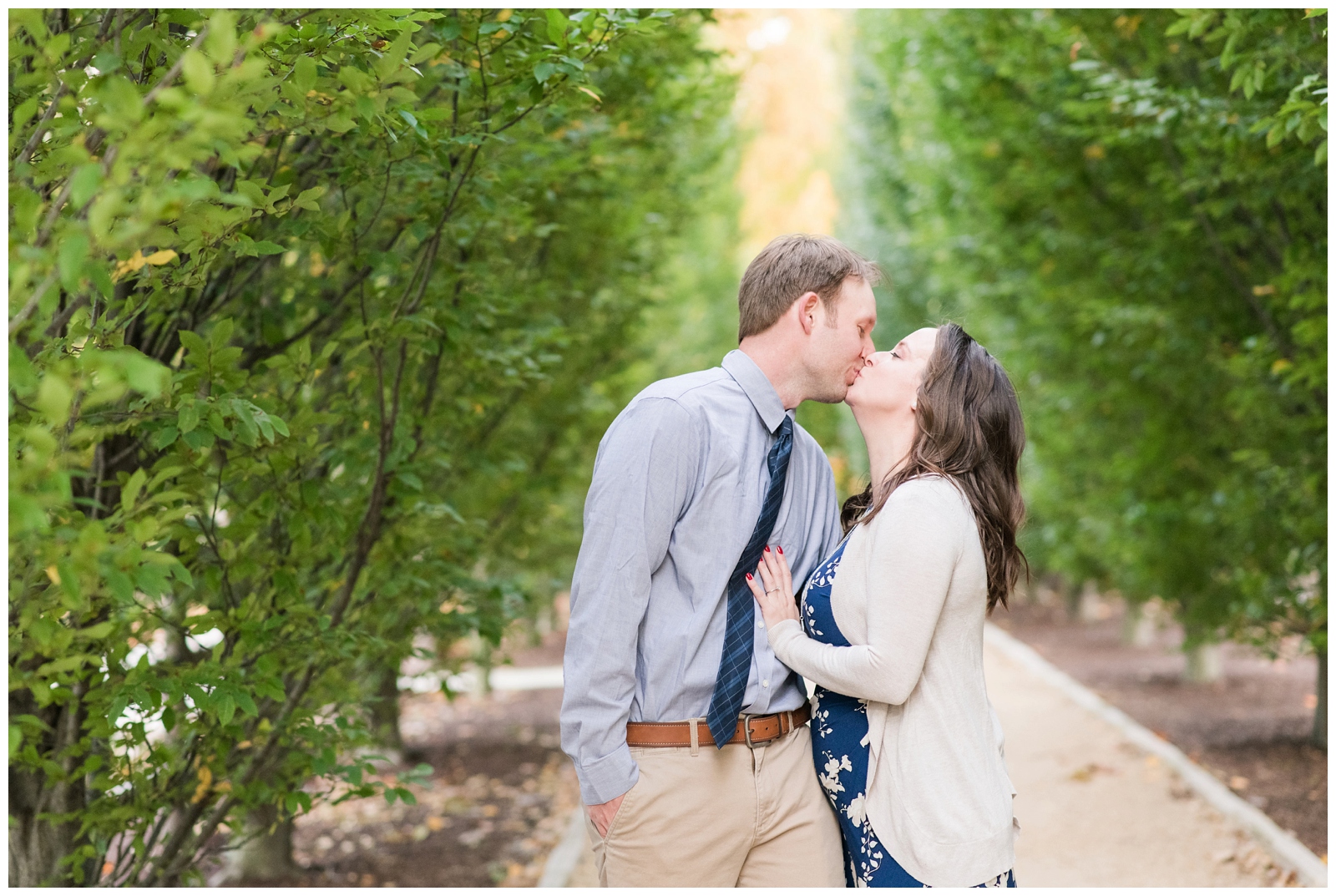 engaged couple kisses among trees at Franklin Park Conservatory during engagement portraits