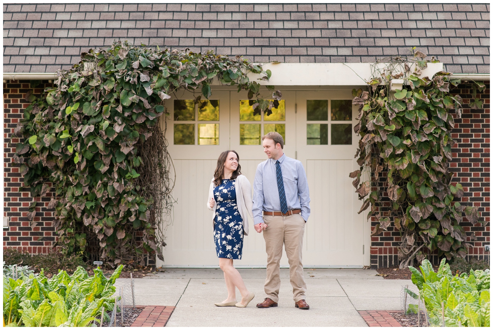 bride and groom hold hands while looking at each other in front of white wood doors with ivy