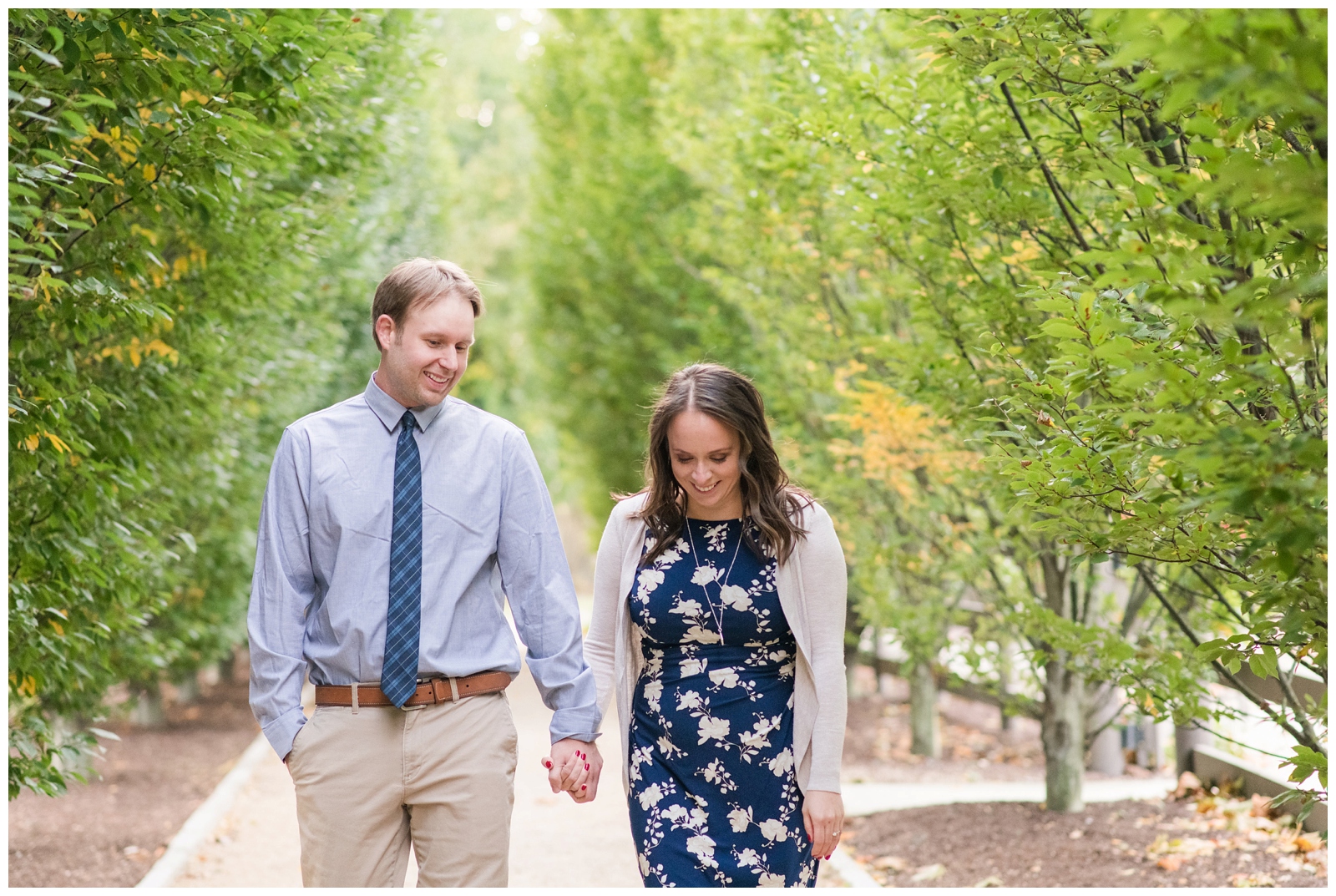 engaged couple holds hands and walks between trees in Columbus, Ohio