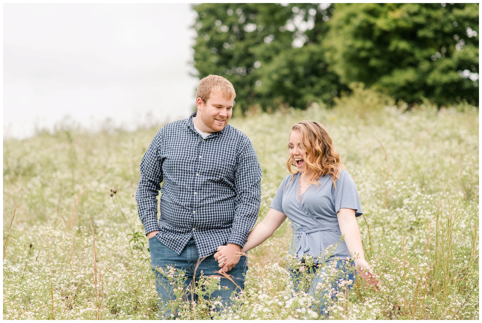 bride and groom cheer in tall field at Dawes Arboretum during engagement portraits