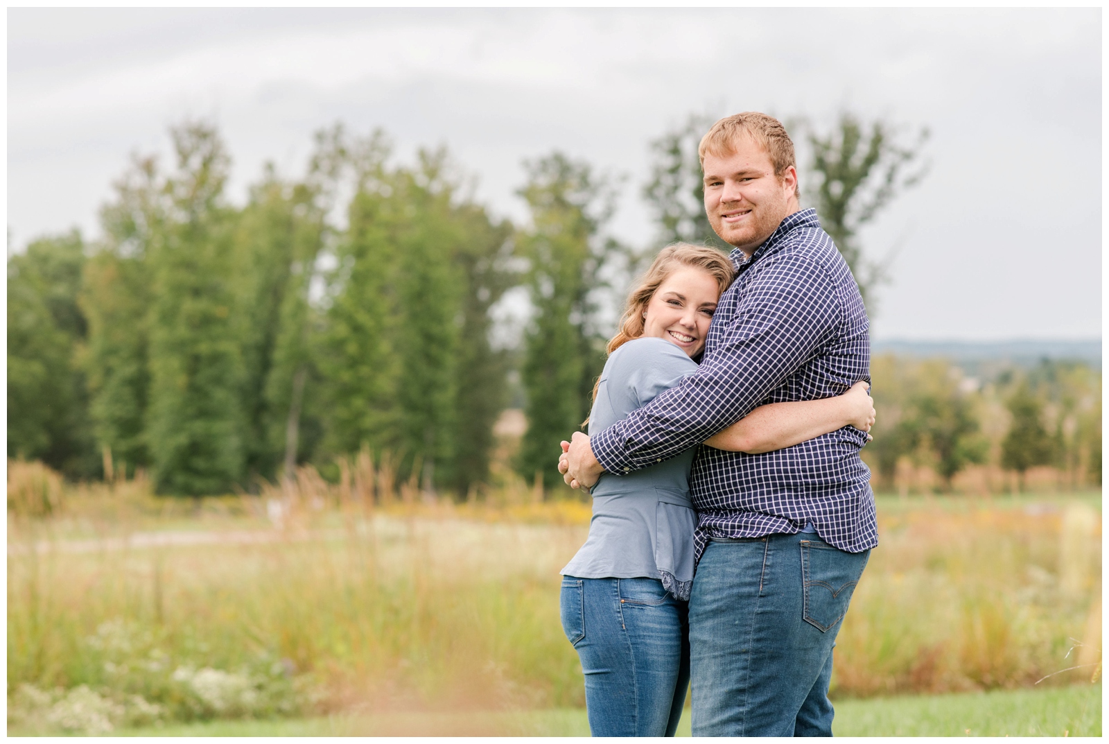 Ohio couple hugs in field at Dawes Arboretum during engagement portraits 