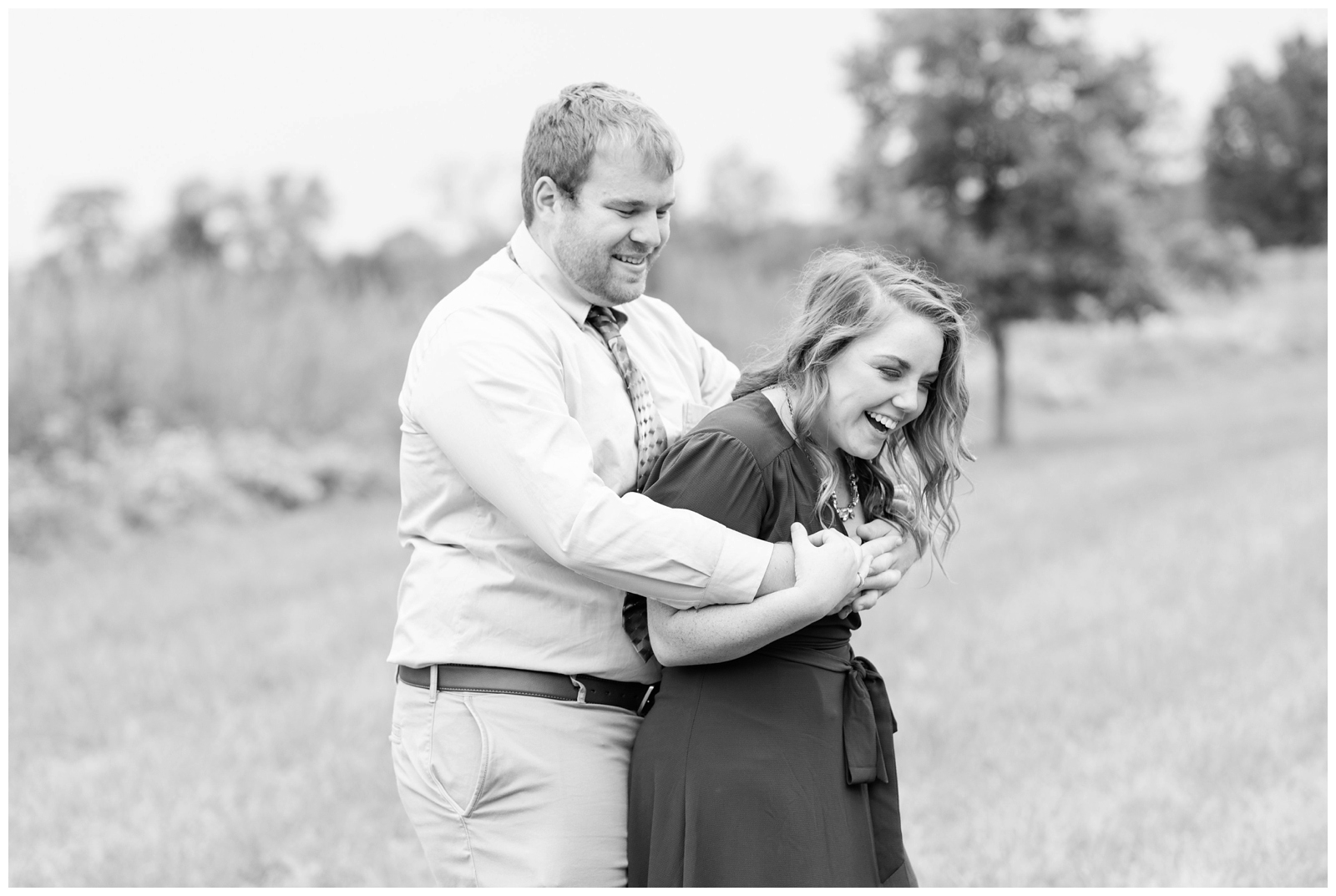 black and white photo of groom hugging bride and laughing during summer engagement session Dawes Arboretum