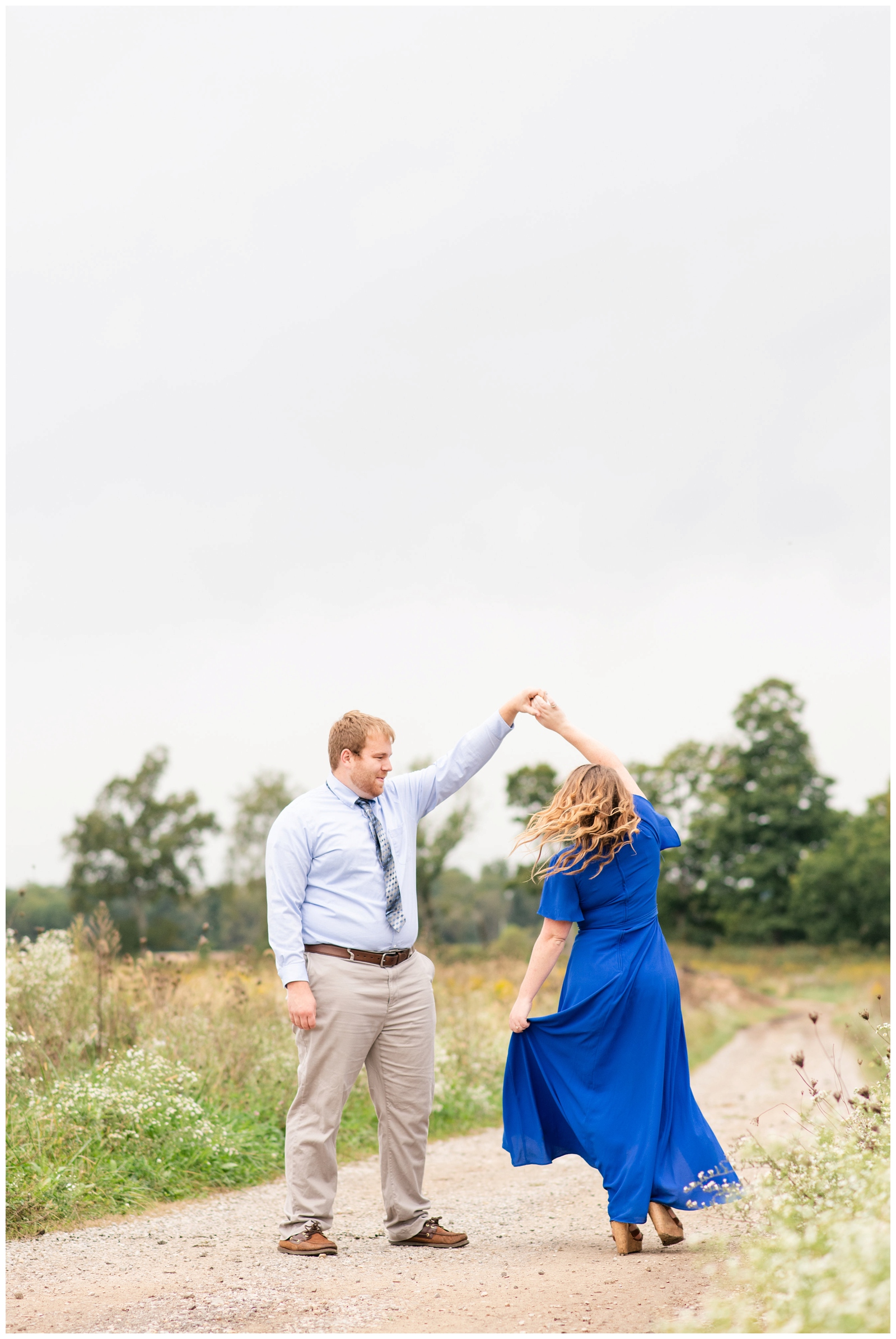 bride and groom dance along walkway at summer engagement session Dawes Arboretum