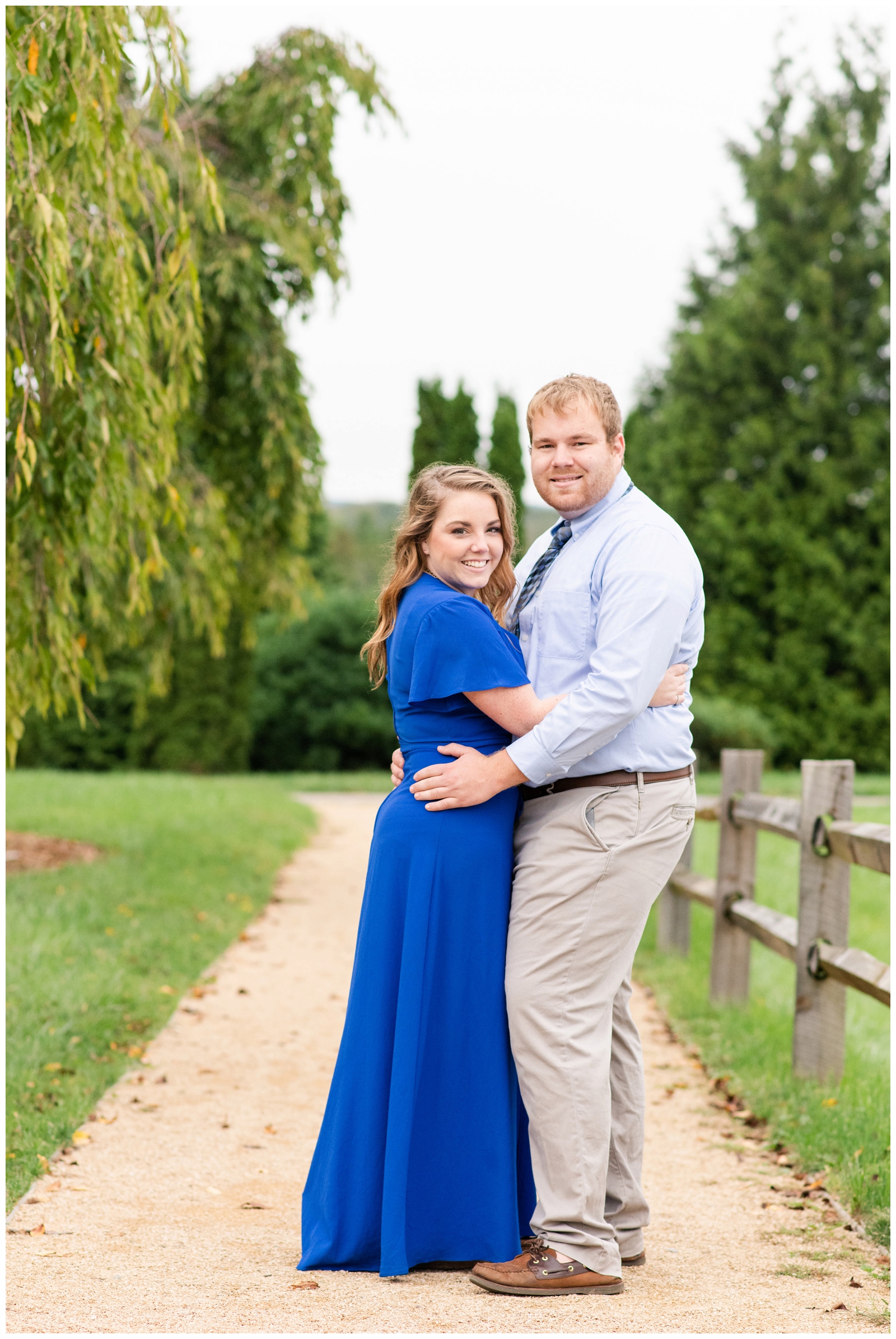 bride in bright blue dress hugs groom during summer engagement portraits at Dawes Arboretum