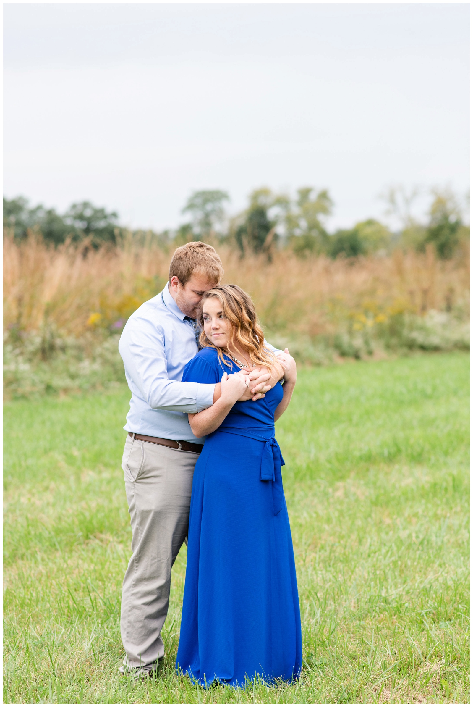 bride stands with back to groom during engagement portraits in field at Dawes Arboretum
