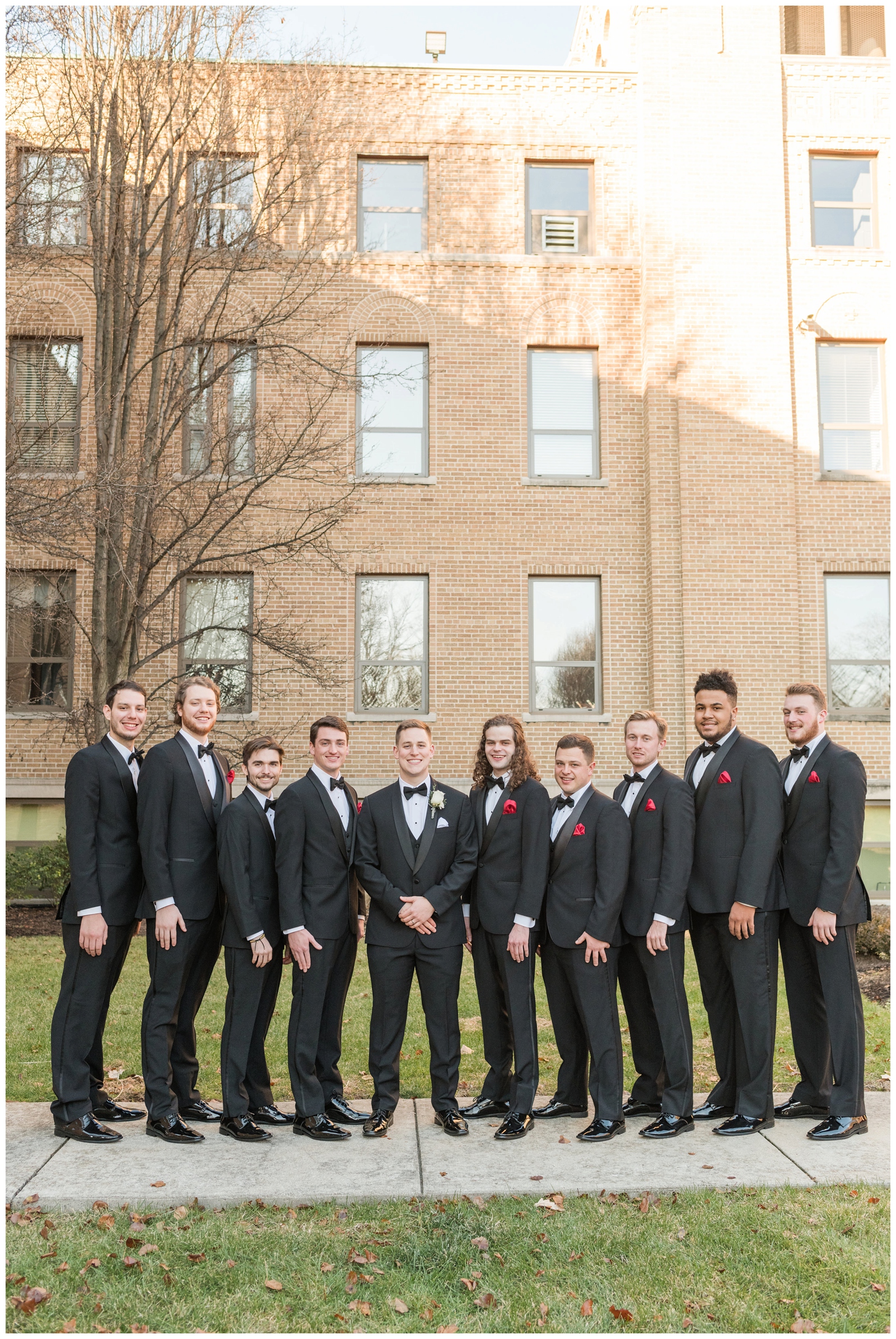 groomsmen in black suits stand next to Ohio groom before Christmas wedding