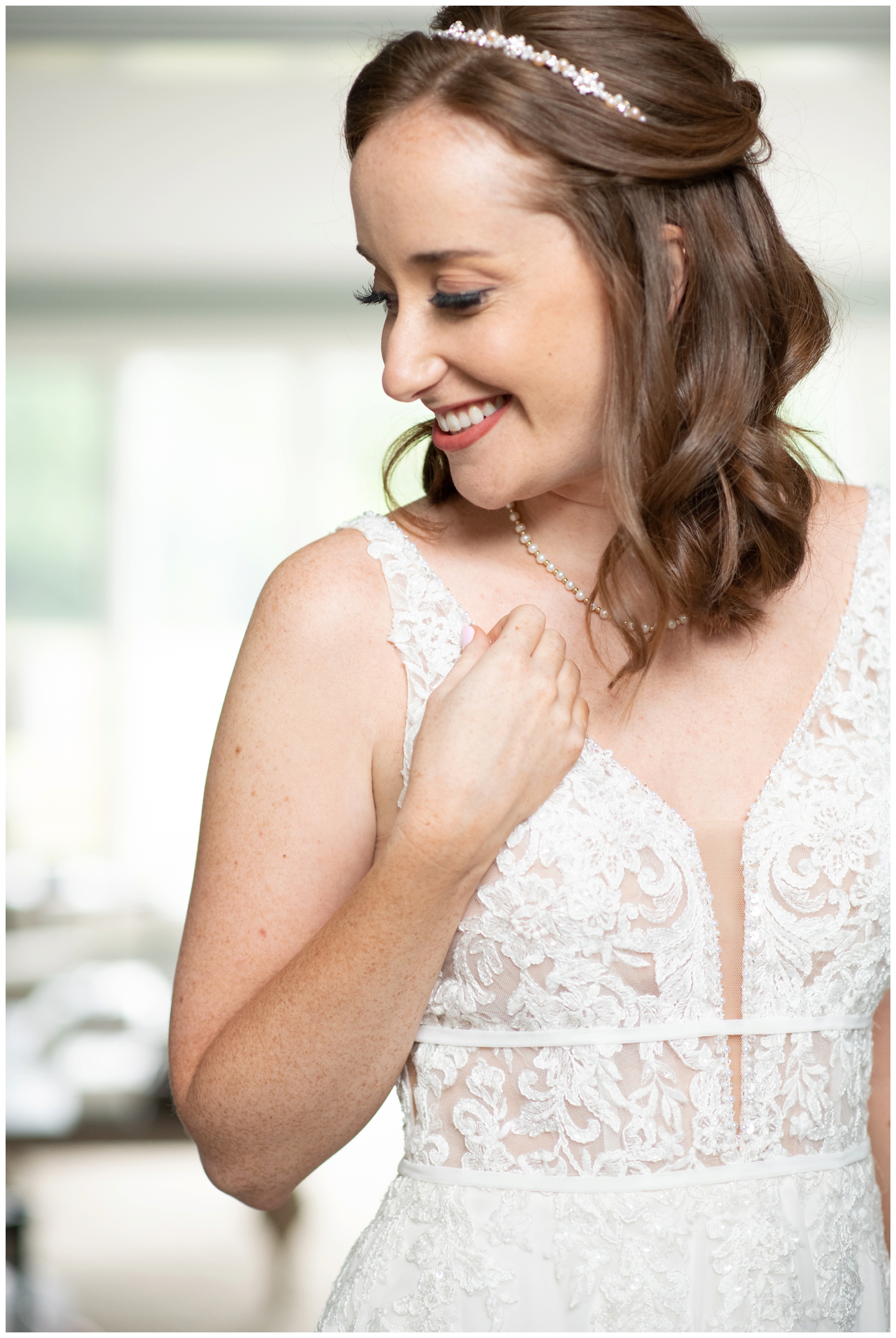 bride holds edge of wedding dress and looks over shoulder smiling
