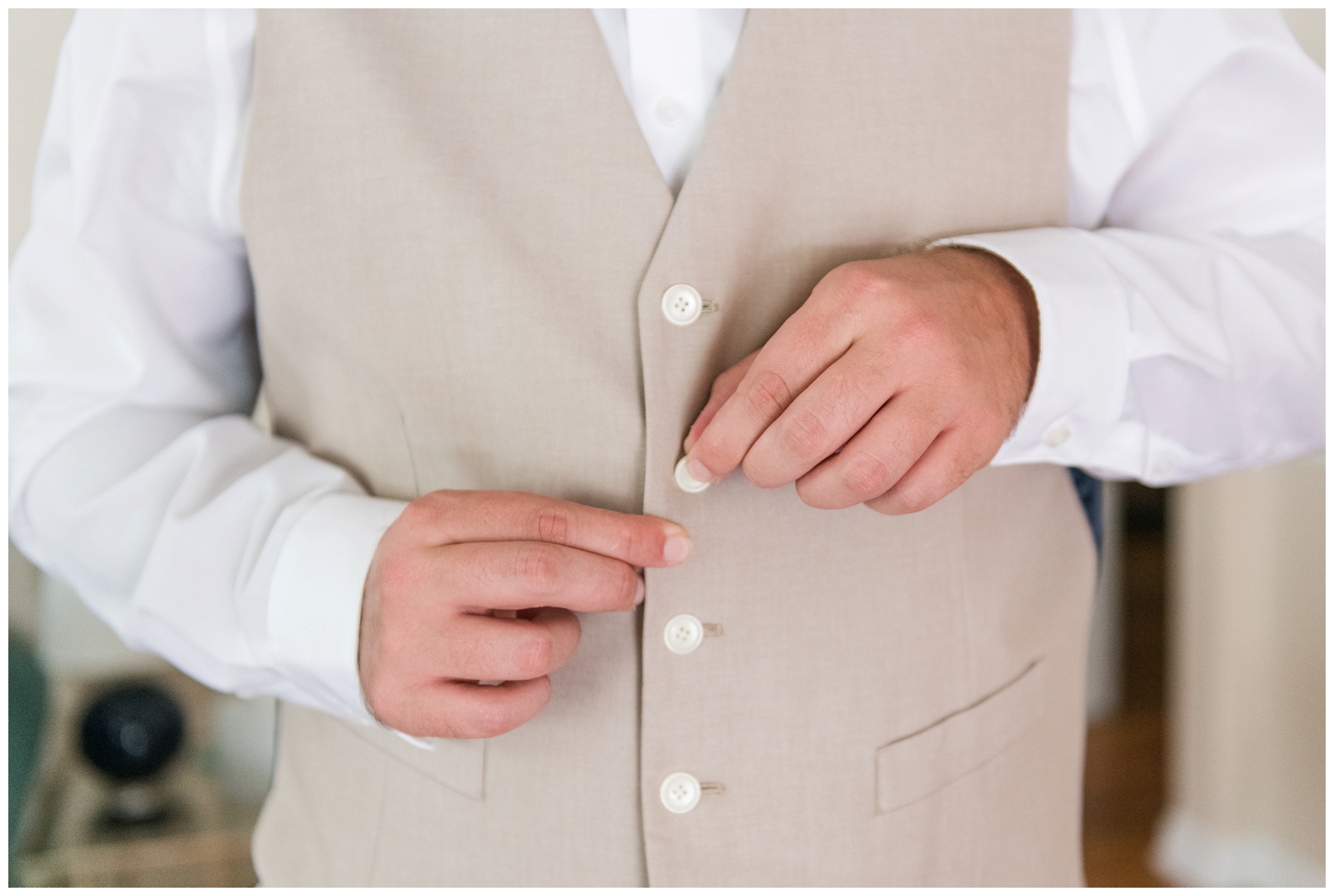 groom adjusts buttons on vest while preparing for Ohio wedding