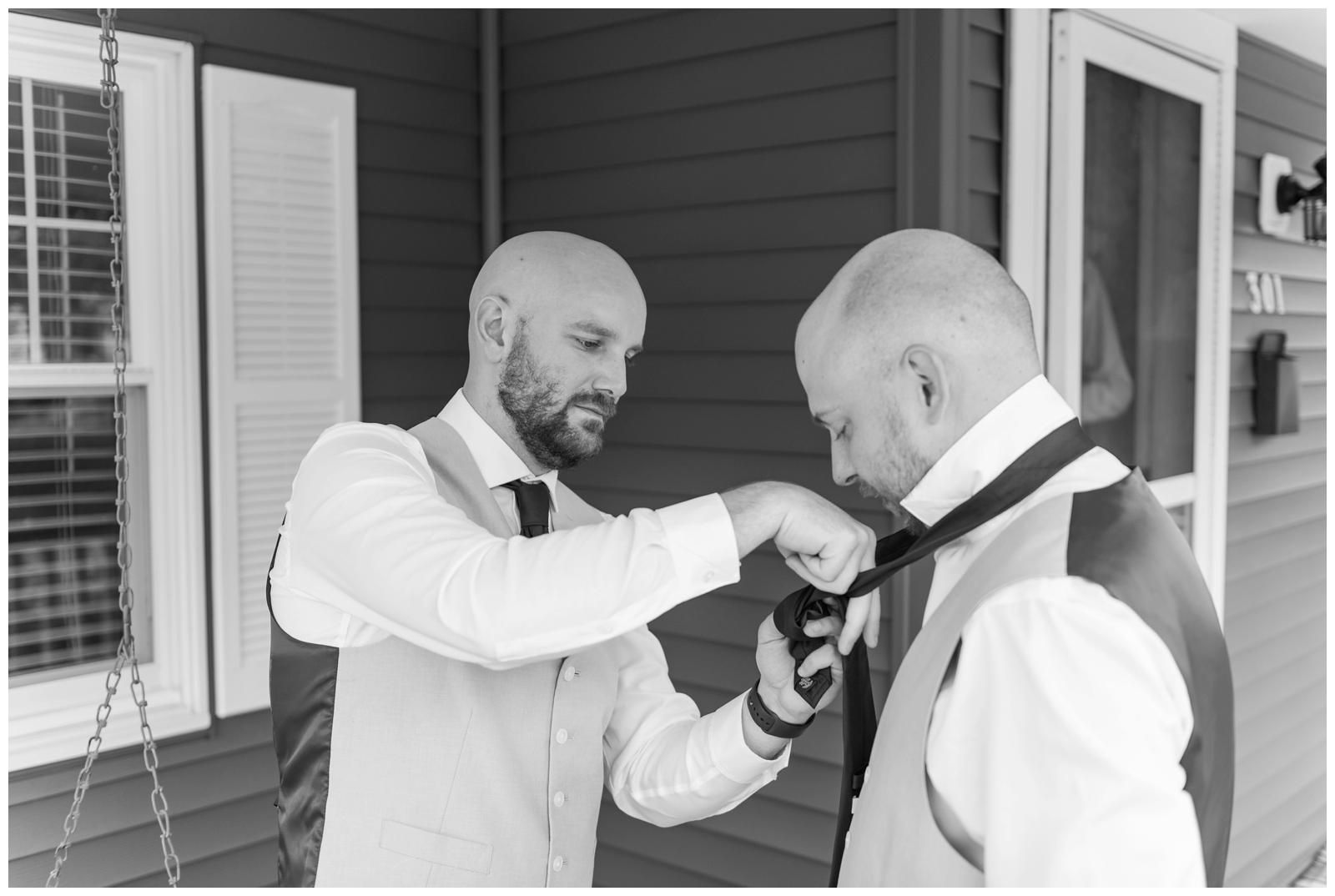 groomsman ties tie for groom outside home