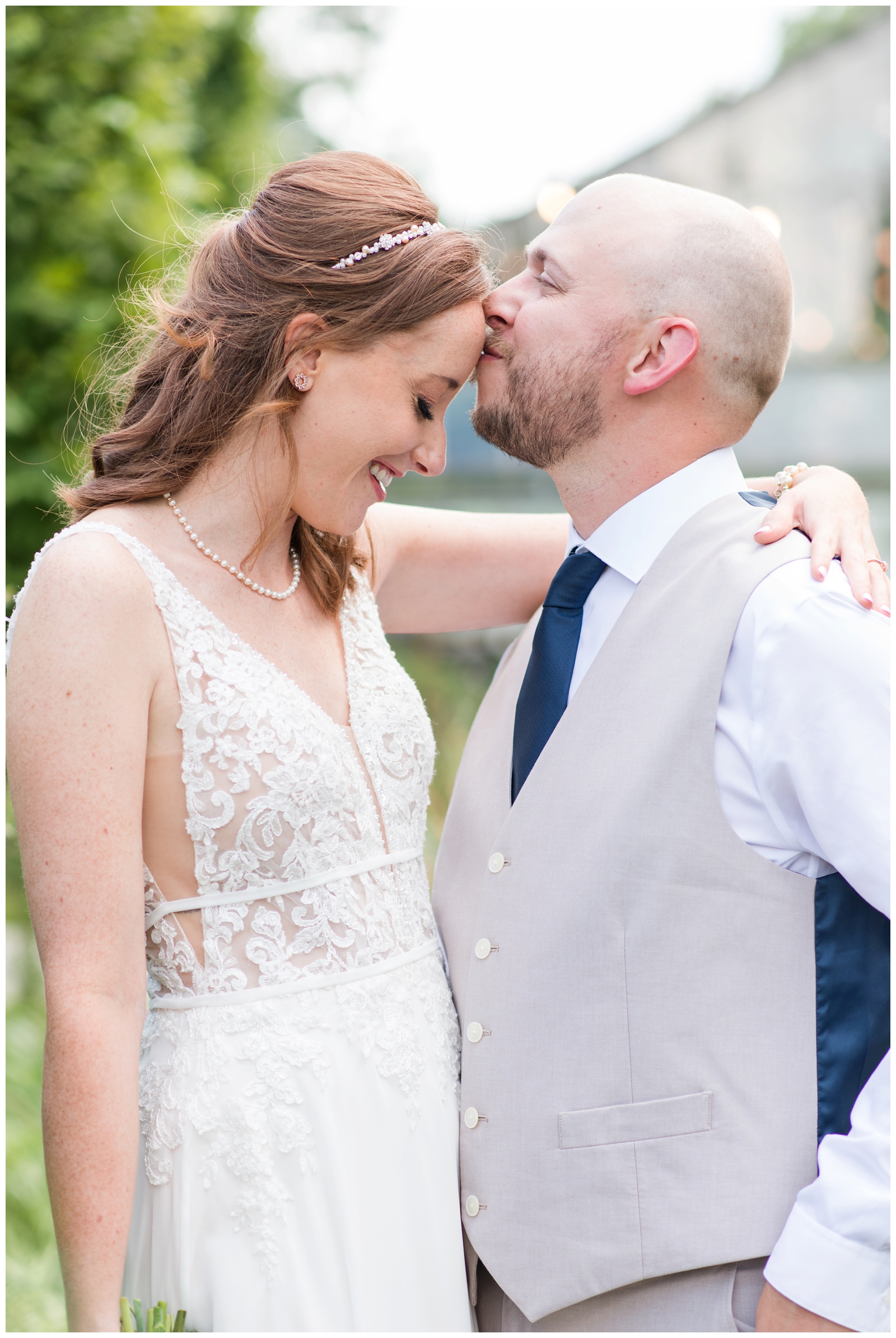 groom kisses bride's forehead during summer wedding portraits in Ohio