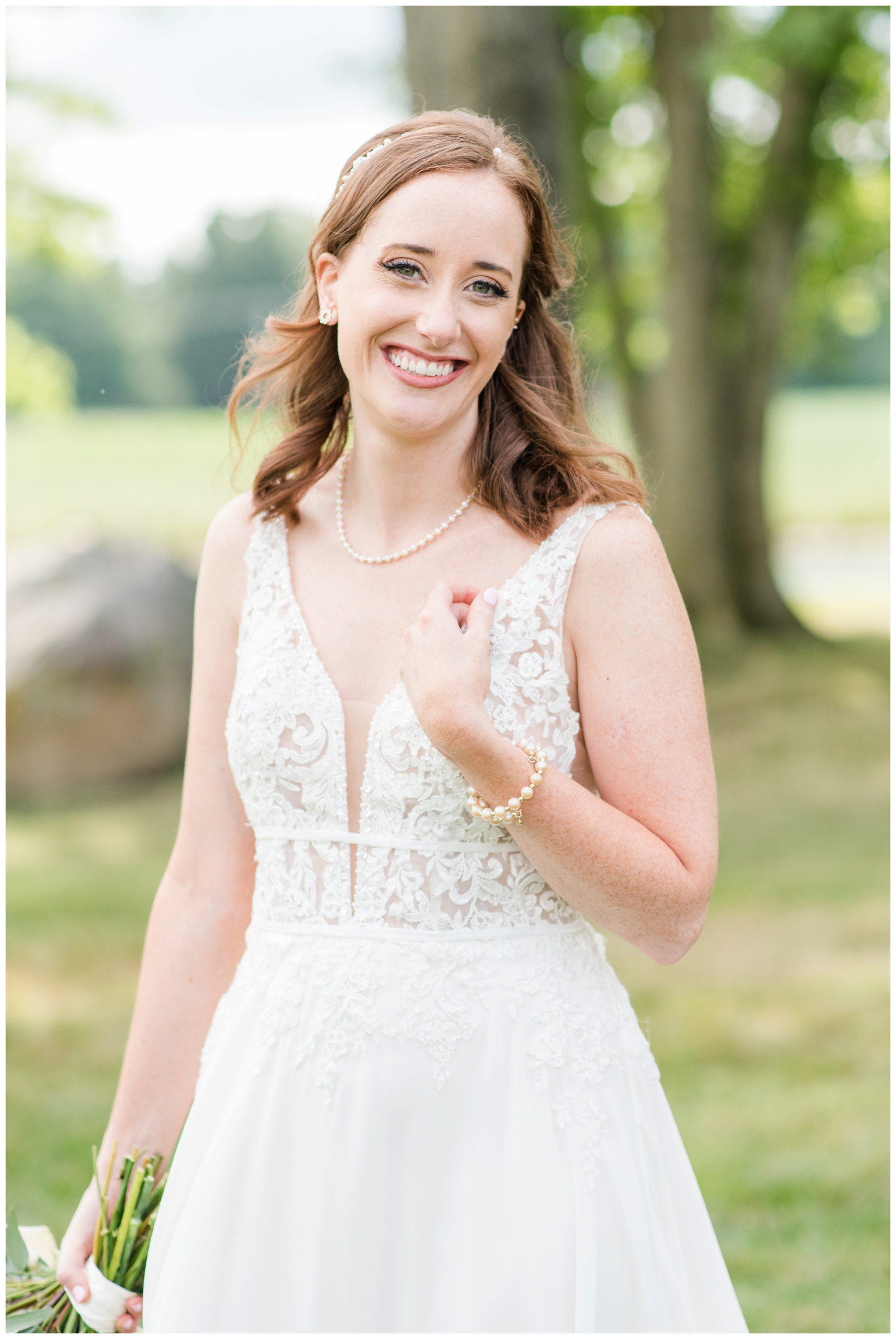 Ohio bride poses with hand on wedding dress showing off pearl bracelet 