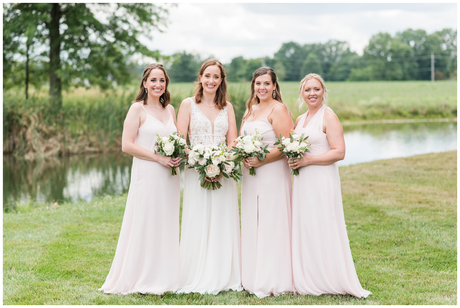 bride poses with three bridesmaids in pale pink dresses