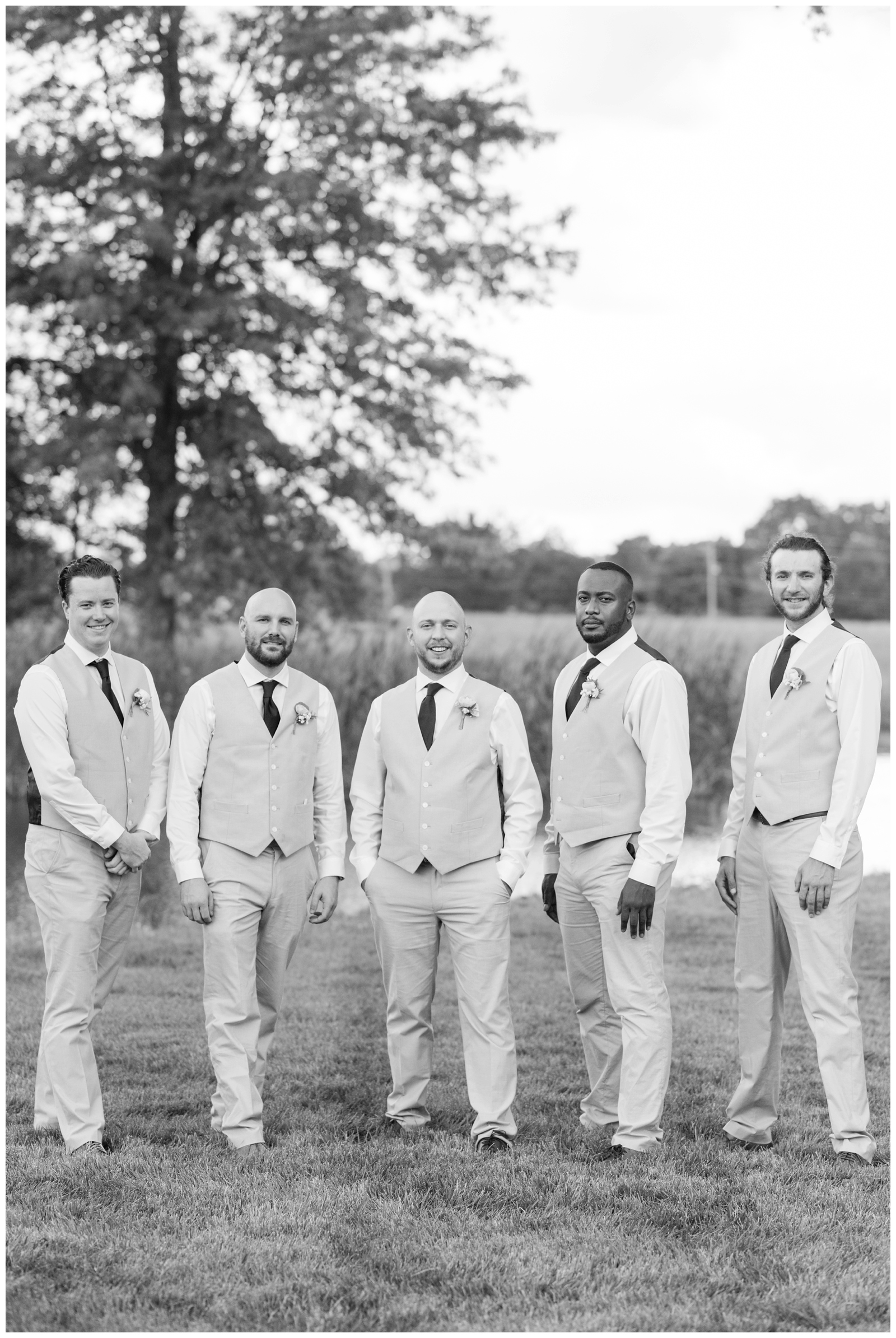 groom stands with four groomsmen by river at Oak Grove Jorgensen Farms