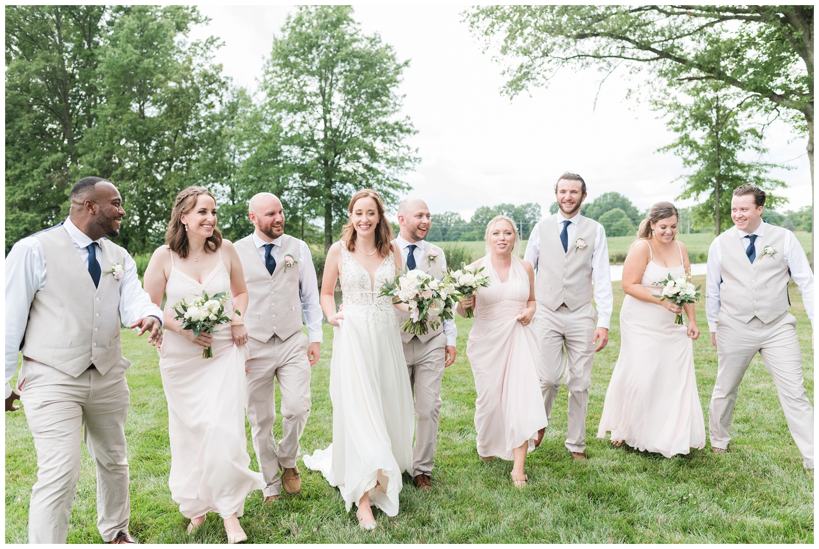 bridal party walks with bride and groom through farm