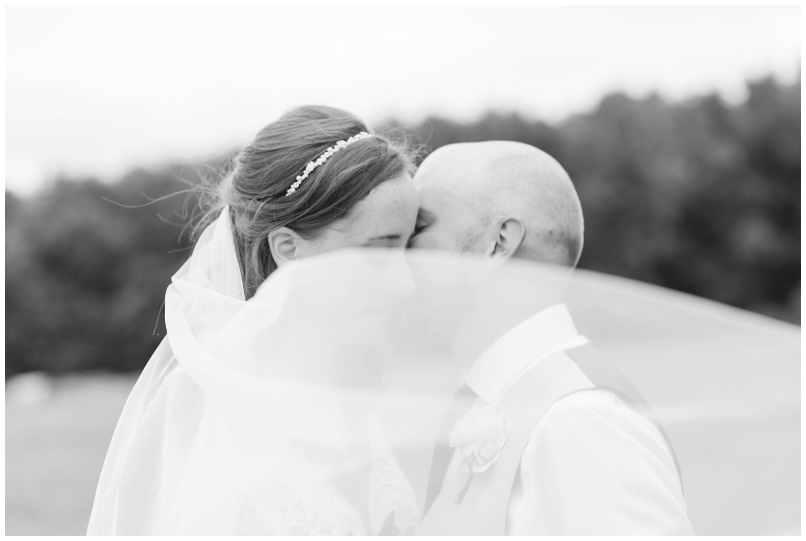 groom whispers to bride while veil floats around them