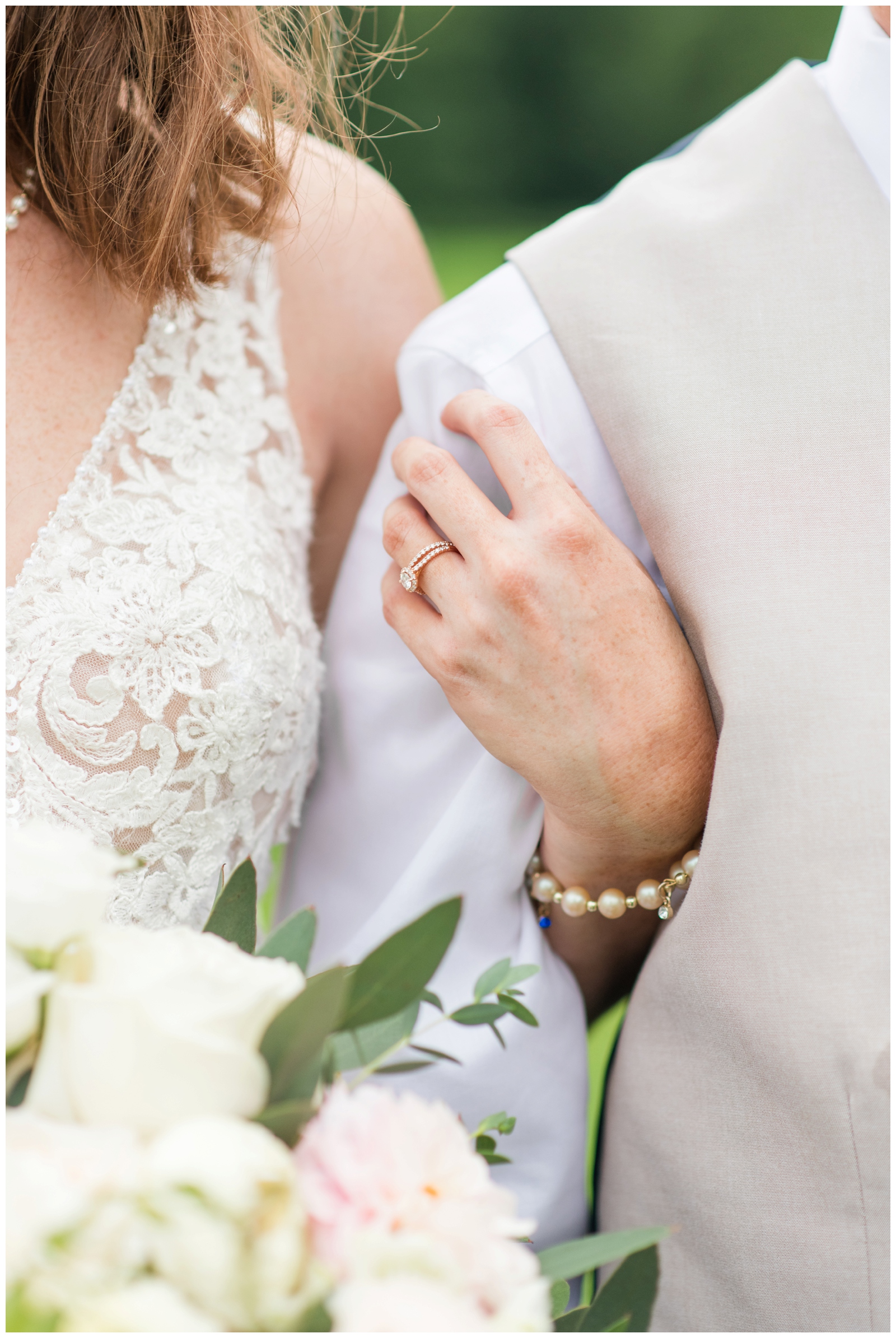 bride holds groom's arm, showing off wedding rings