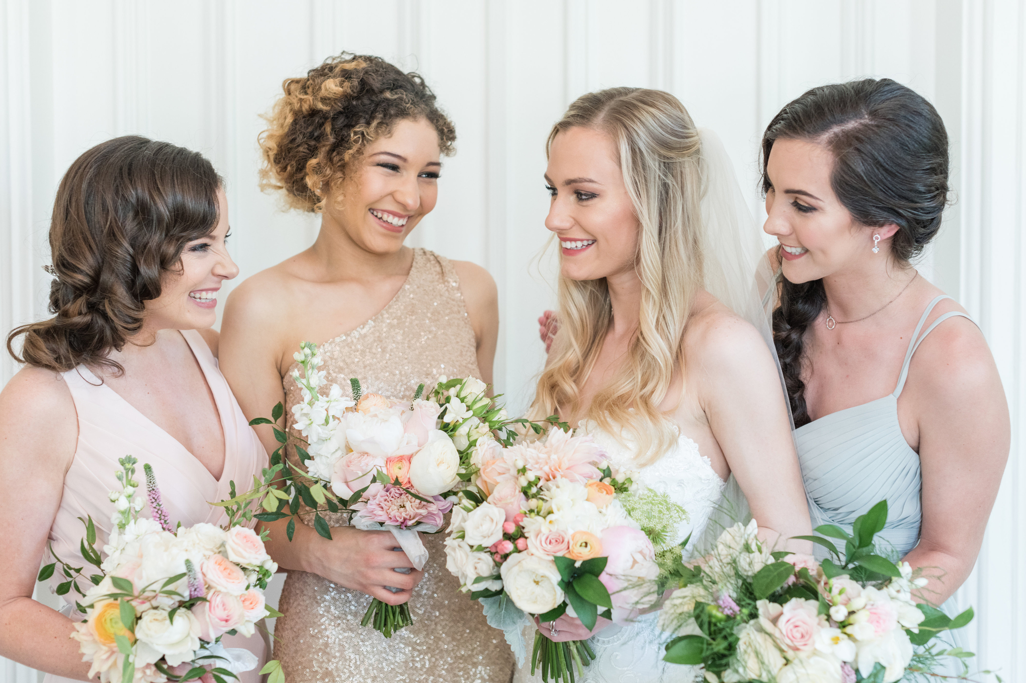 A bride smiles big with her bridesmaids with their matching bouquets at Magnolia Hill Farm