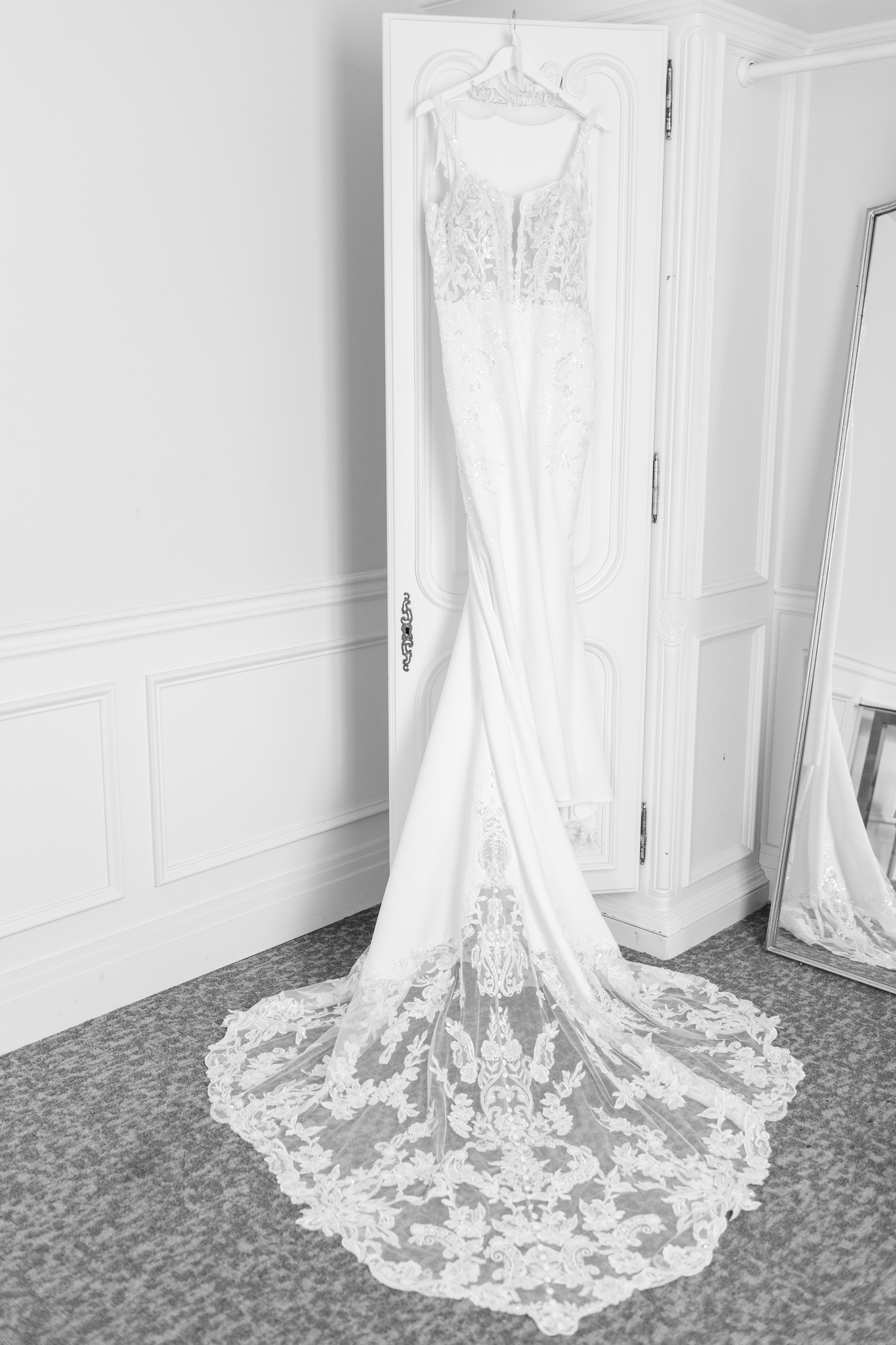 A bride's dress hangs from a door in the getting ready room