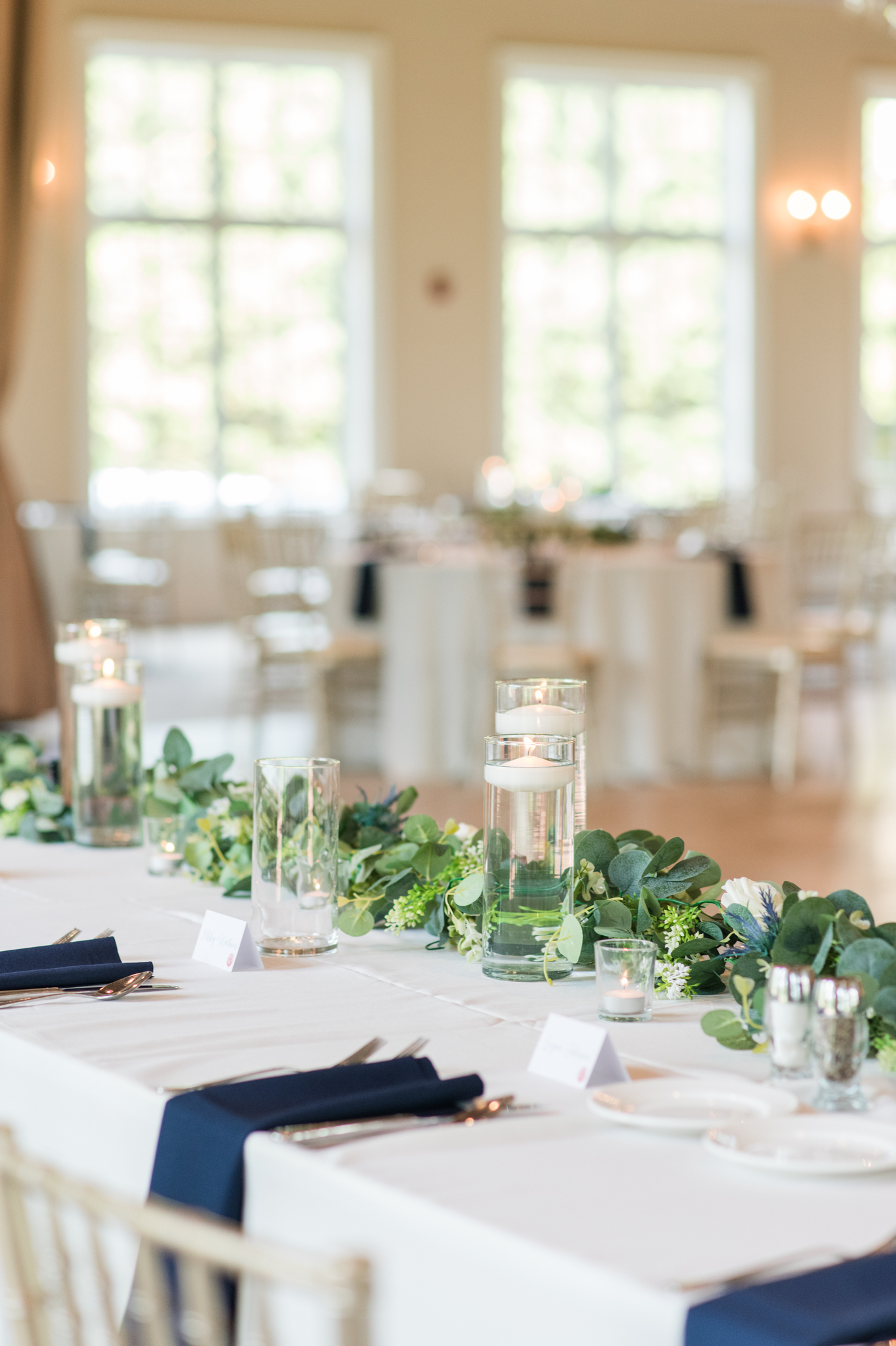 A look at a long table with candles lit and blue napkins on white linen at a wedding reeception