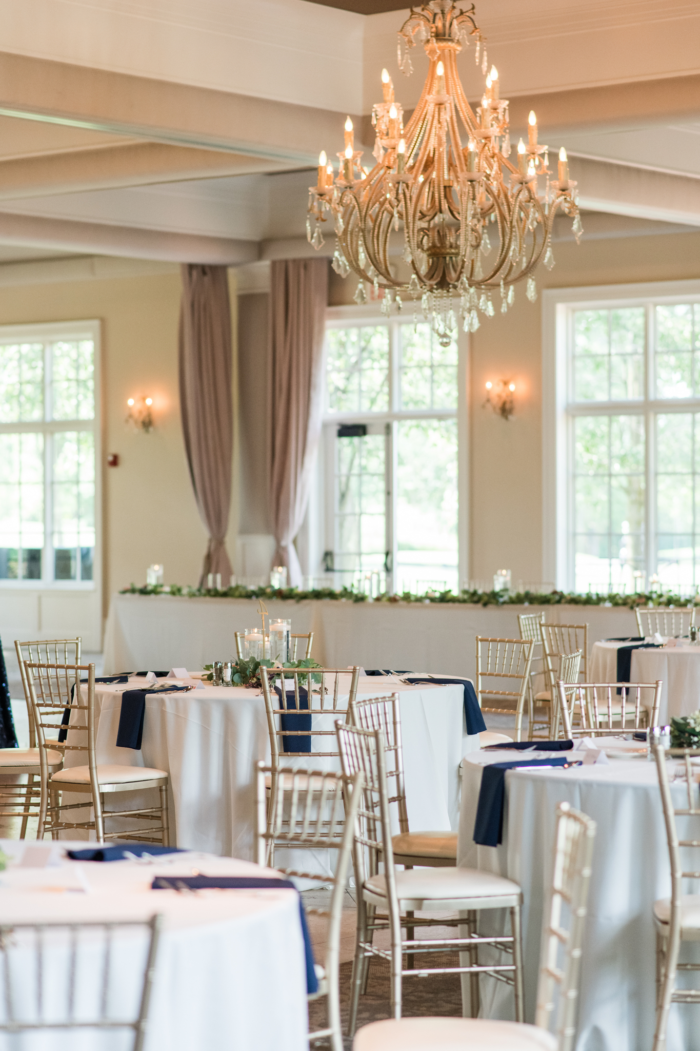 Details of a wedding reception under a chandelier with blue napkins