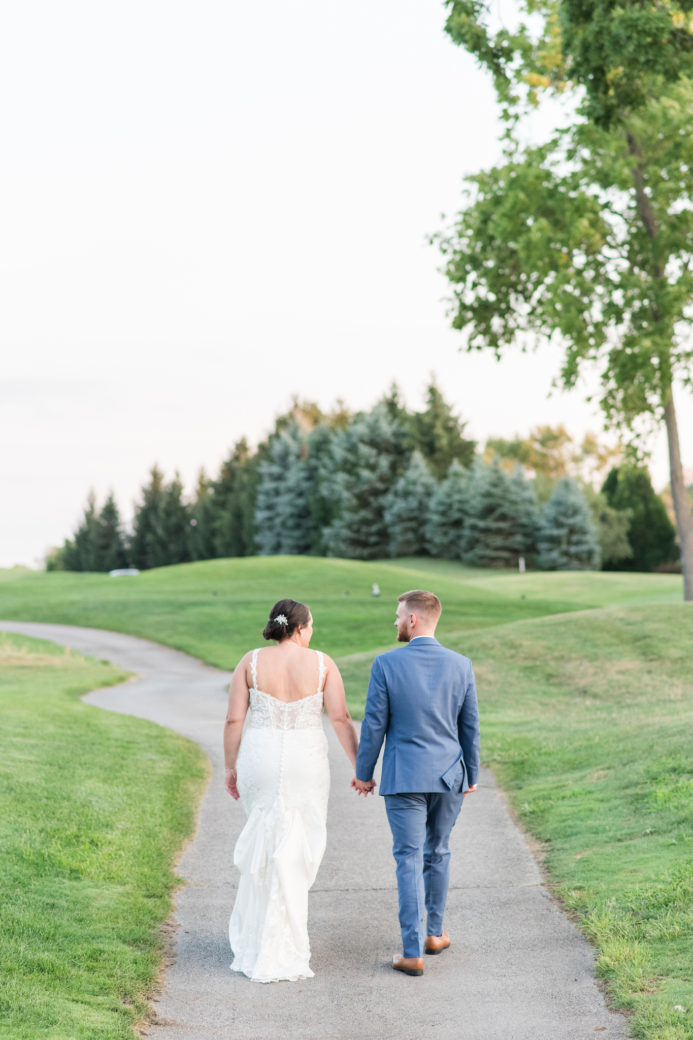 A bride and groom hold hands while walking one of the sidewalks through the Pinnacle Golf Club Wedding venue