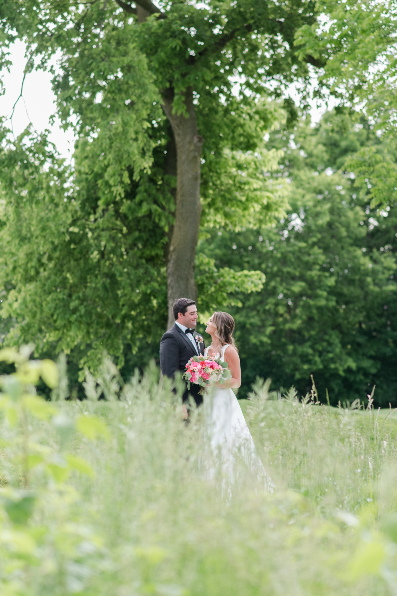 Newlyweds snuggle and smile at each other in the tall grass of the Pinnacle Golf Club Wedding venue