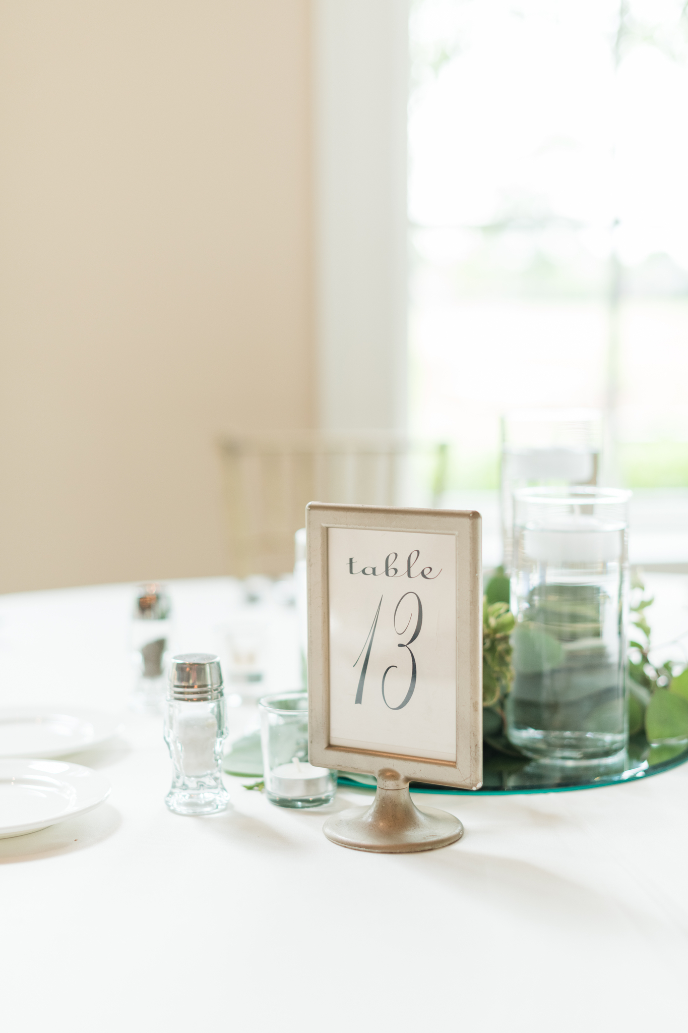 Details of a table setting with candles and table number on white linen