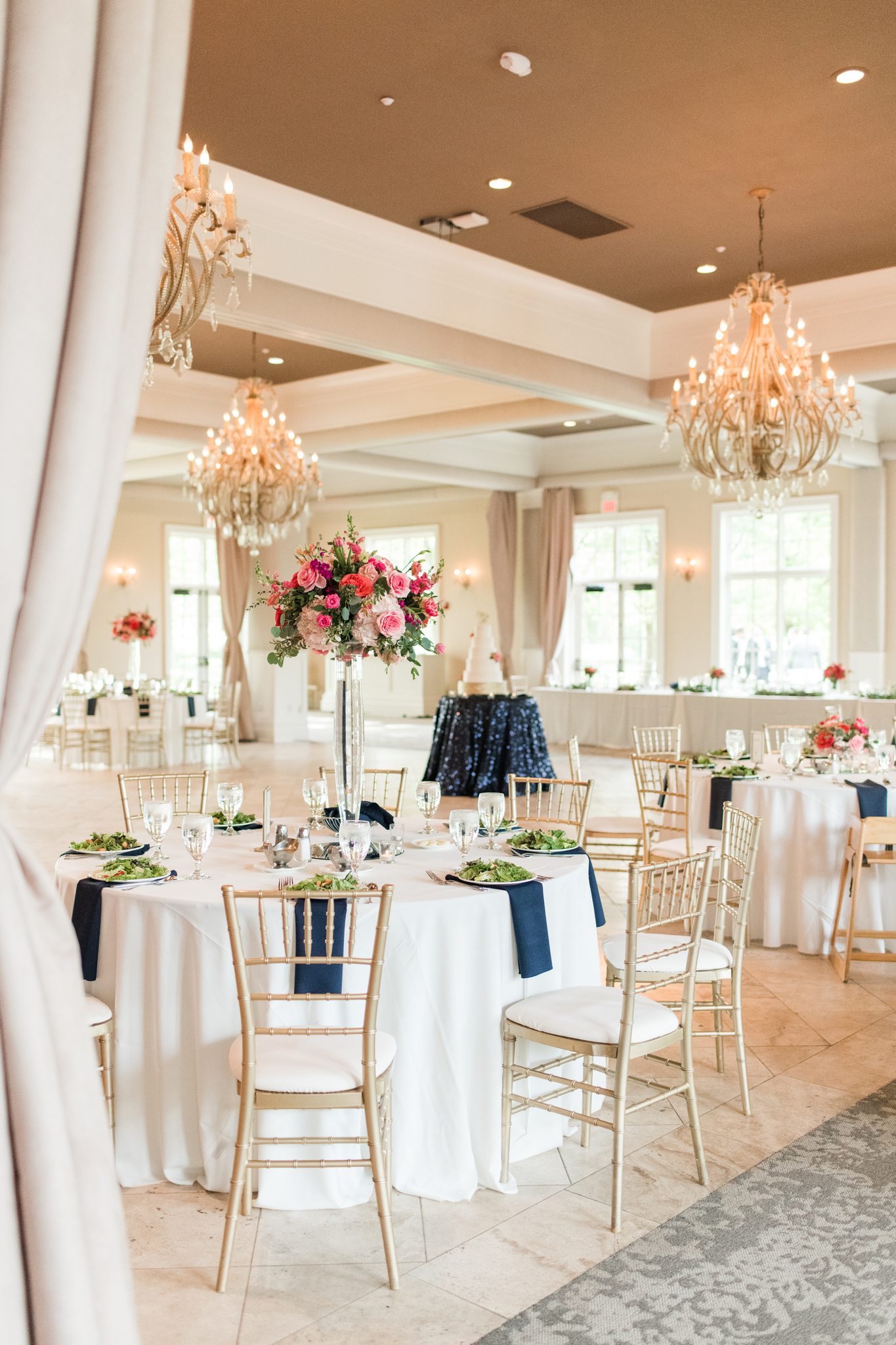 Details of a Pinnacle Golf Club Wedding reception set up under chandeliers with white linen and blue napkins