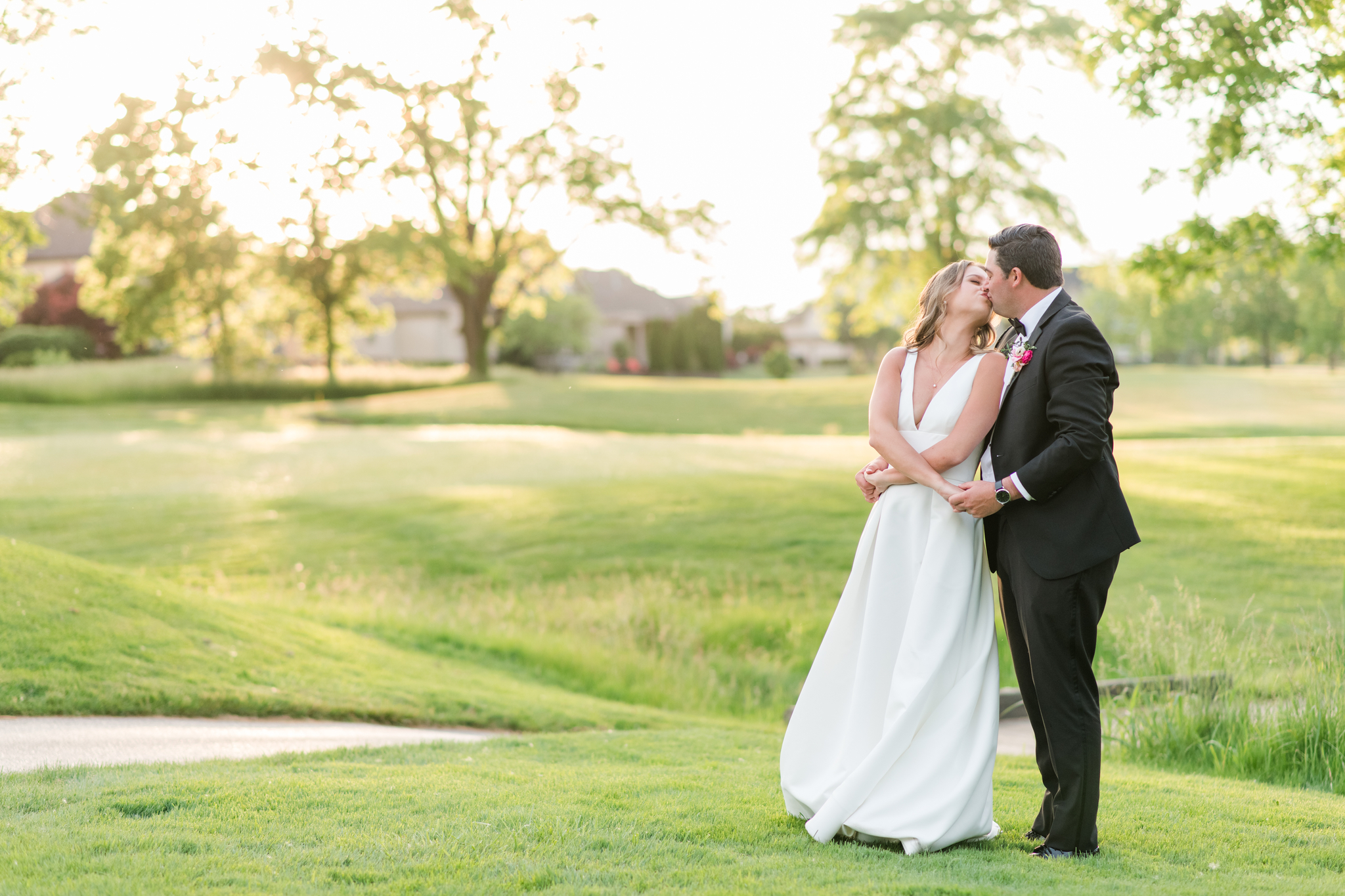 Newlyweds kiss on a knoll at sunset during their Pinnacle Golf Club Wedding