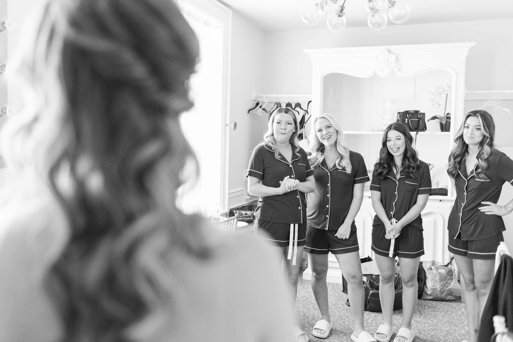 Bridesmaids in pajamas admire the bride in her dress for her reveal
